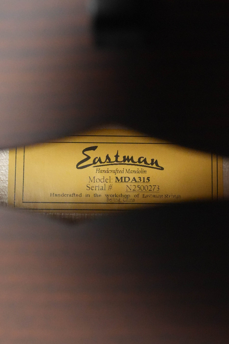 A close-up through the sound hole of an Eastman MDA315 Classic Finish Mandola #0273 shows its label, stating a solid spruce top and reading: Handcrafted in the workshop of Eastman Guitars, Beijing, China.