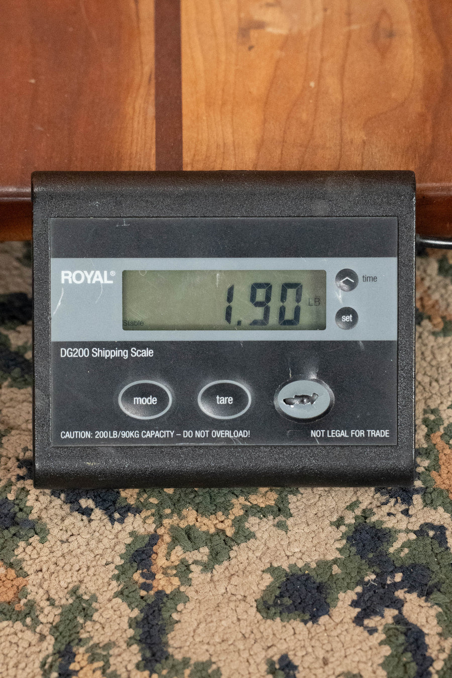 A ROYAL DG200 digital scale displays 1.90 lb on a carpet next to wood, ready to weigh the Eastman Guitars PCH-M104-GB Solid Spruce/Laminated Mahogany Goldburst Flattop A-Style Mandolin #0065.
