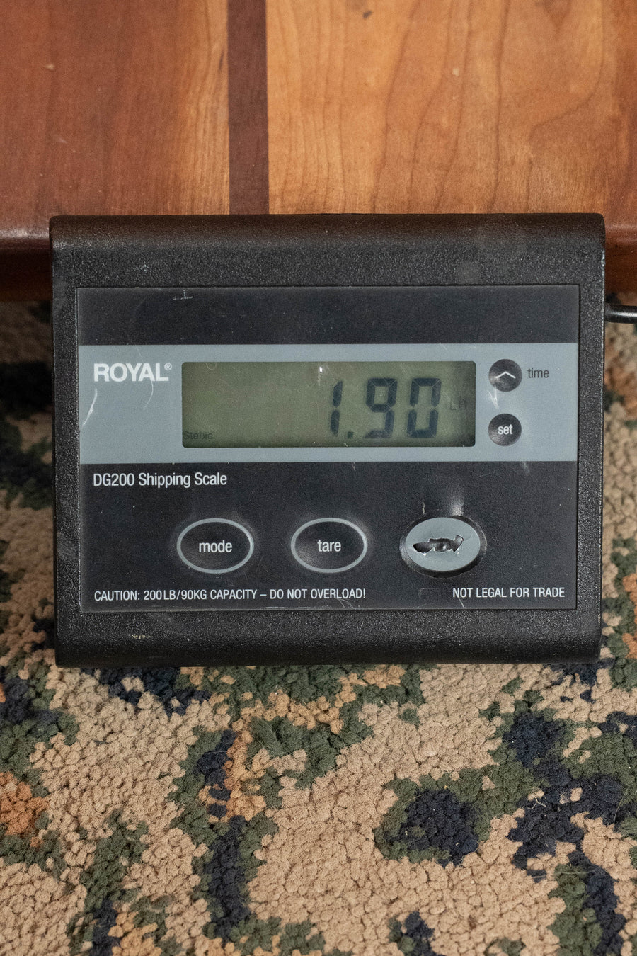 A digital shipping scale on a patterned carpet shows 1.90 pounds—ideal for weighing your Eastman Guitars PCH-M104-GB Solid Spruce/Laminated Mahogany Goldburst Flattop A-Style Mandolin #1876 before shipping.