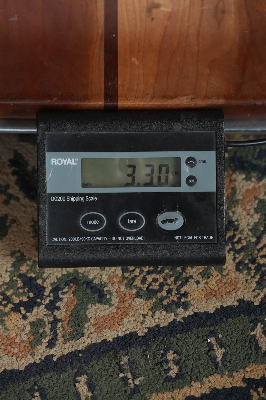 A digital shipping scale shows 3.30 pounds. On a patterned carpet, part of an Eastman Guitars PCH2-TG Thermo-Cured Solid Sitka/Laminated Rosewood Travel Acoustic Guitar (#8013) is seen in the background.
