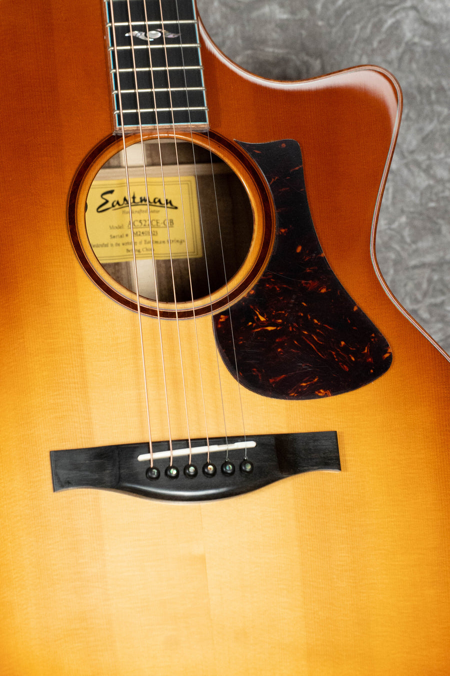 Close-up of a *Dread-Not Certified Used* Eastman Guitars AC522CE-GB Grand Auditorium, showing the European Spruce/Mahogany Goldburst body, sound hole with brand label, and LR Baggs pickup visible.