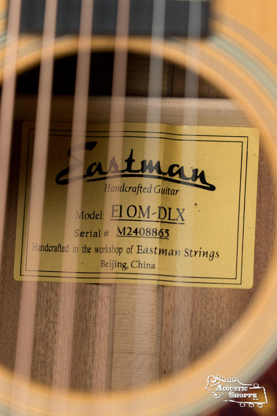 Close-up of Eastman E1OM-DLX acoustic guitar label behind strings, showing Sitka spruce top and K&K pickup system. - (Used) Eastman E1OM-DLX All Solid Sitka/Sapele Guitar w/K&K Pickup #8865 - Default Title