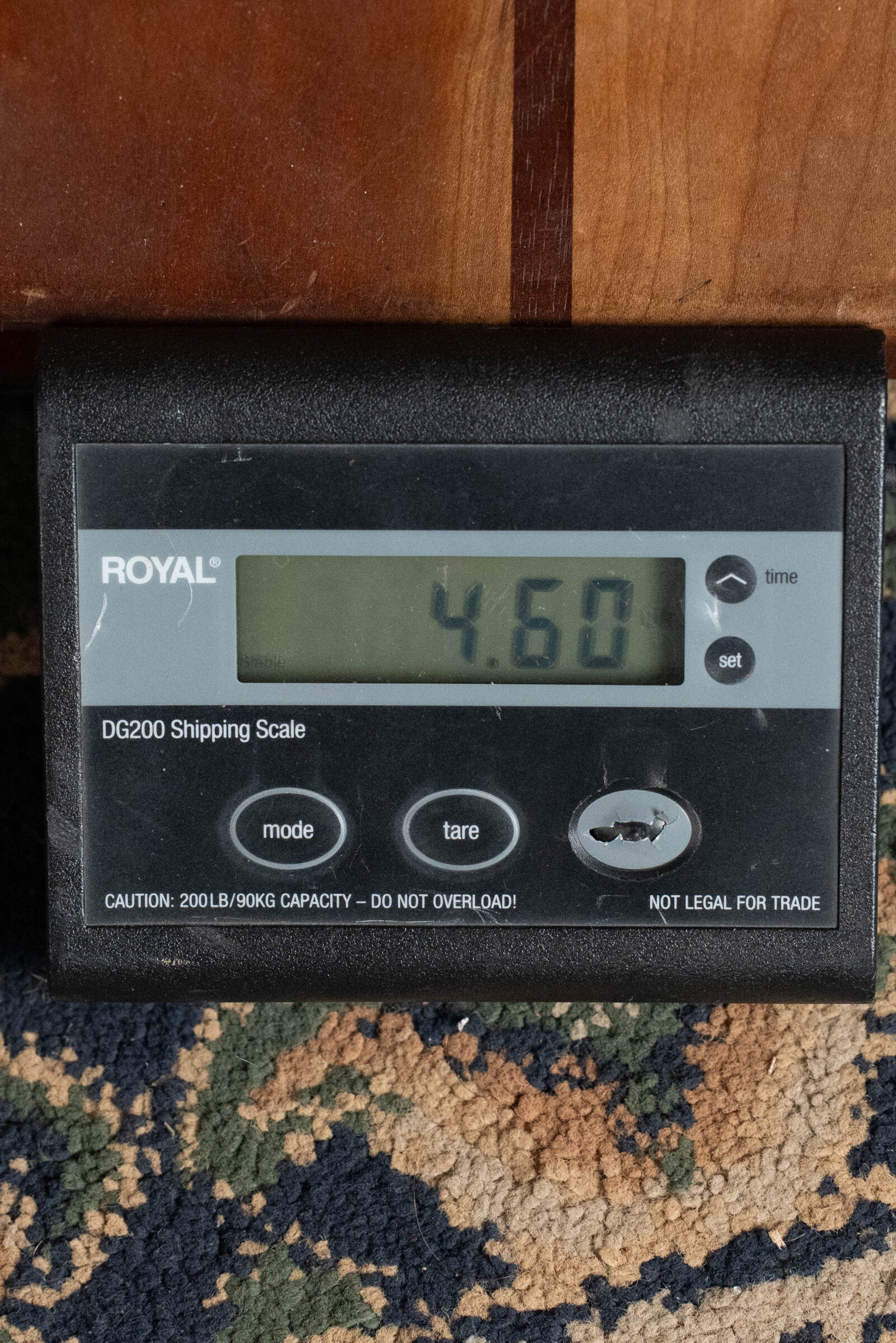 A digital shipping scale shows 4.60 with the Eastman Guitars E20D-TC Thermo-Cured Adirondack/Rosewood Dreadnought Acoustic Guitar #8128 resting above on a wooden surface, all placed on a patterned carpet.