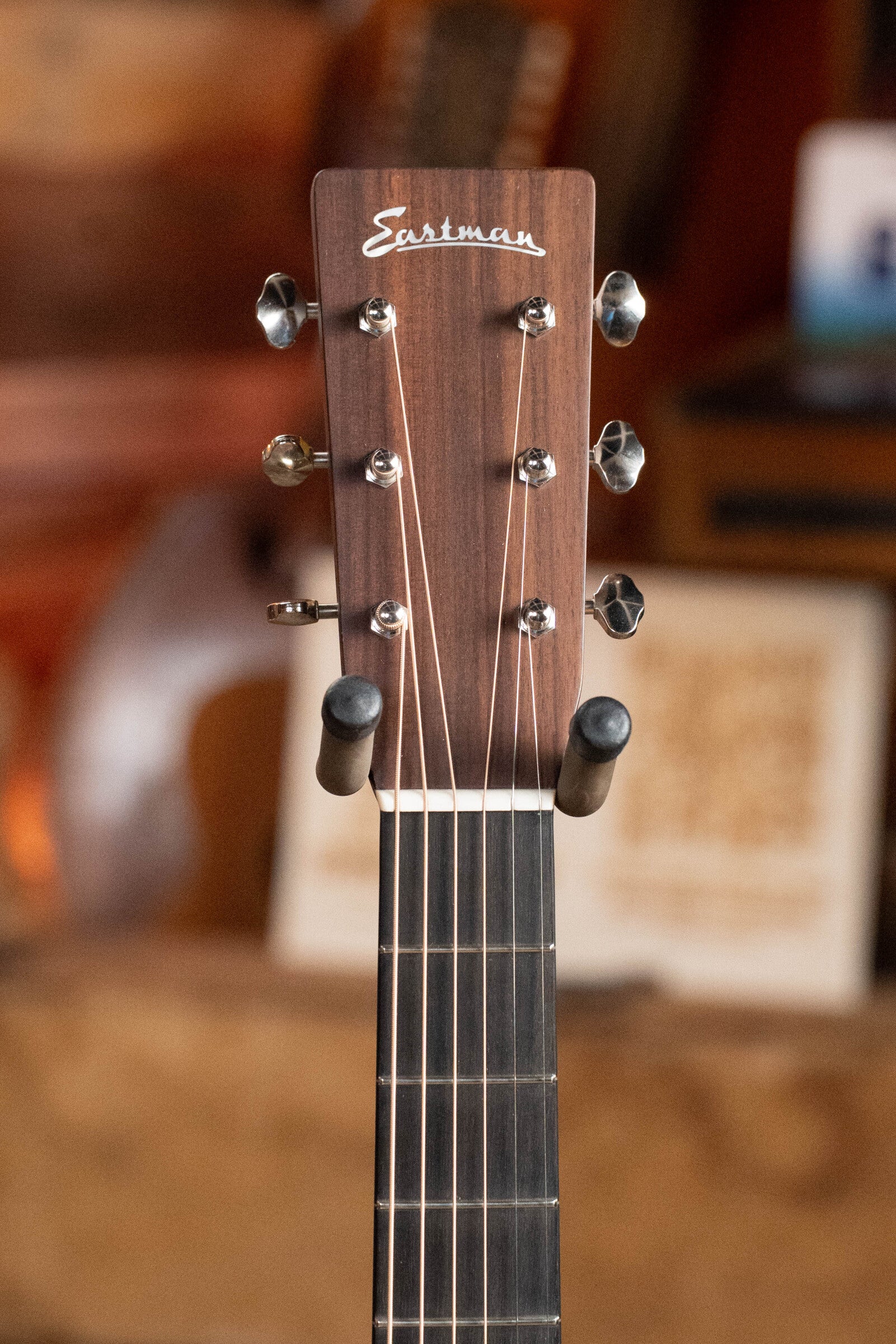 Close-up of the headstock of the Eastman Guitars E20D-TC Thermo-Cured Adirondack/Rosewood Dreadnought Acoustic Guitar (#8128), showing tuning pegs and part of the fretboard against a blurred background.