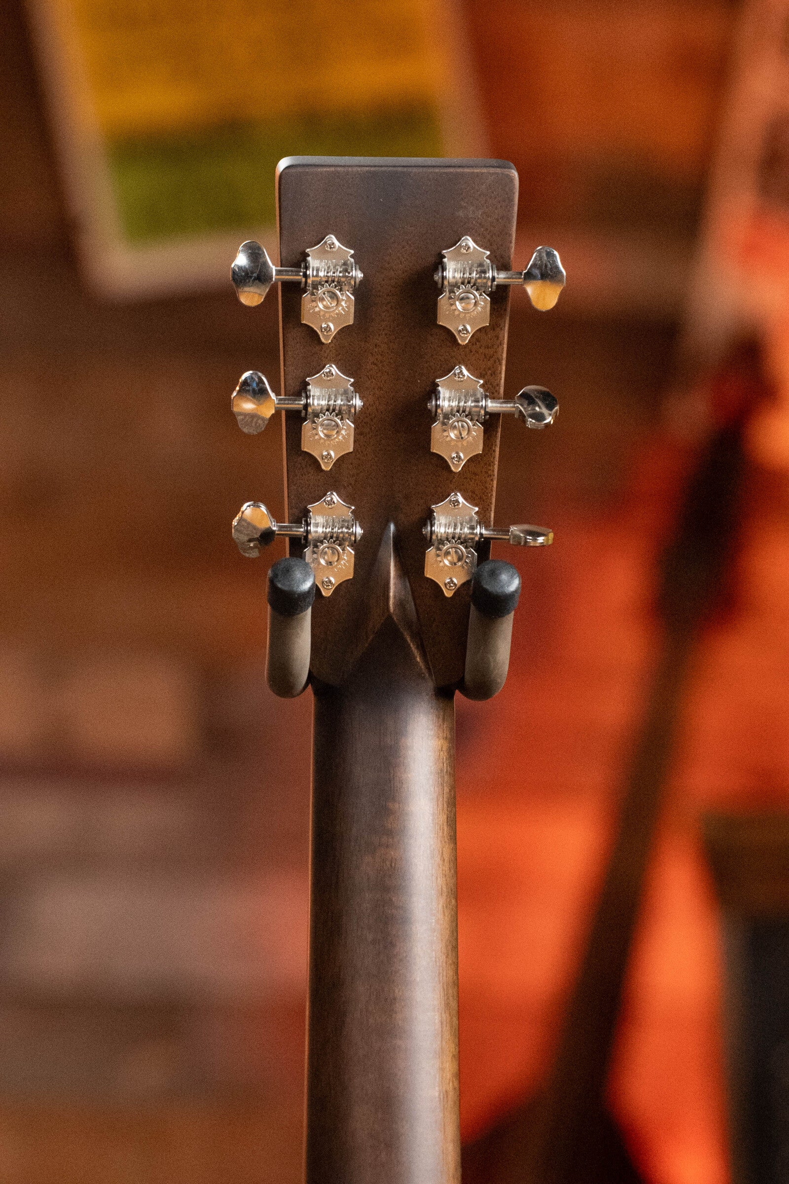 Close-up of the back of an Eastman Guitars E20D-TC Thermo-Cured Adirondack/Rosewood Dreadnought Acoustic Guitar #8128 headstock, displaying six silver tuning pegs against a softly blurred warm-toned background.