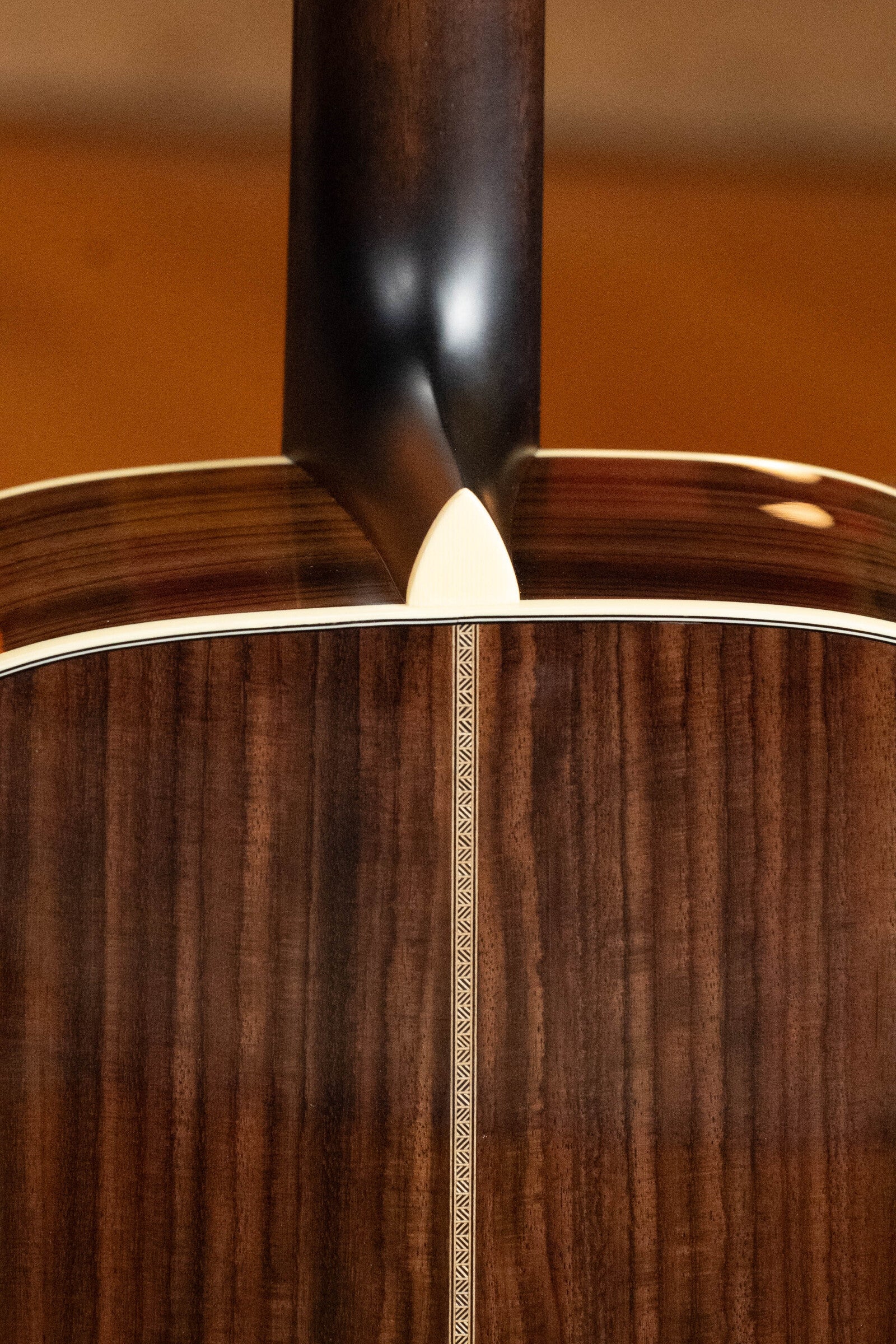 Close-up of the back and neck joint on the Eastman Guitars E20D-TC Thermo-Cured Adirondack/Rosewood Dreadnought Acoustic Guitar #8128, highlighting rich wood grain, decorative back seam inlay, and a smooth, polished finish.