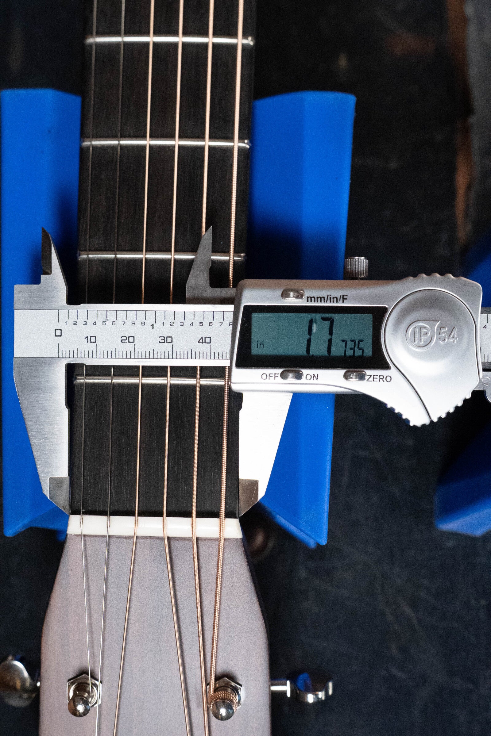 A digital caliper shows 1.725 inches while measuring the neck width above the nut of an Eastman Guitars E20D-TC Thermo-Cured Adirondack/Rosewood Dreadnought Acoustic Guitar #8128, with blue supports securing it.