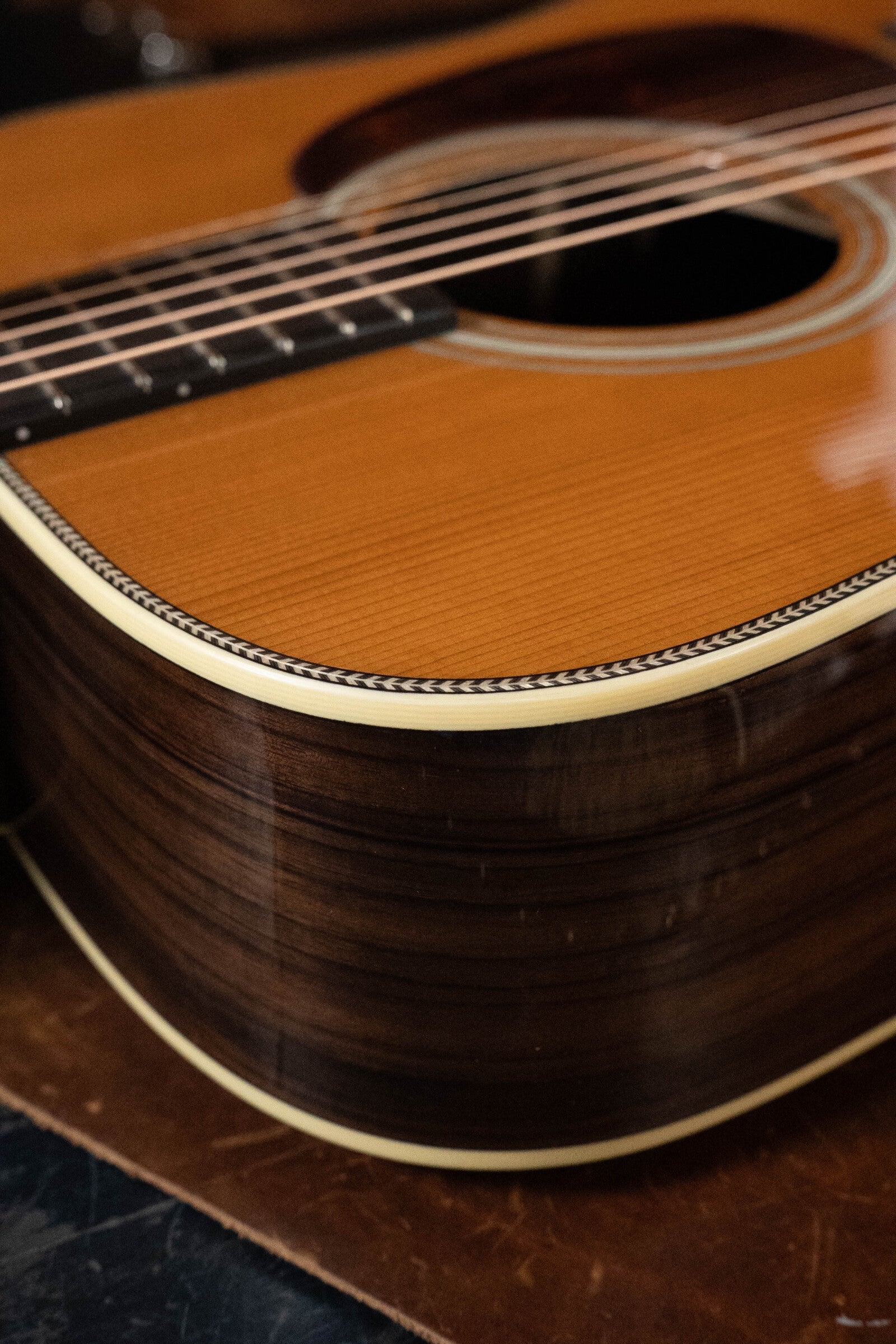 Close-up of the Eastman E20D-TC Thermo-Cured Adirondack/Rosewood Dreadnought by Eastman Guitars, featuring its detailed binding, rich wood grain body, and visible Adirondack Spruce top around the sound hole and strings.