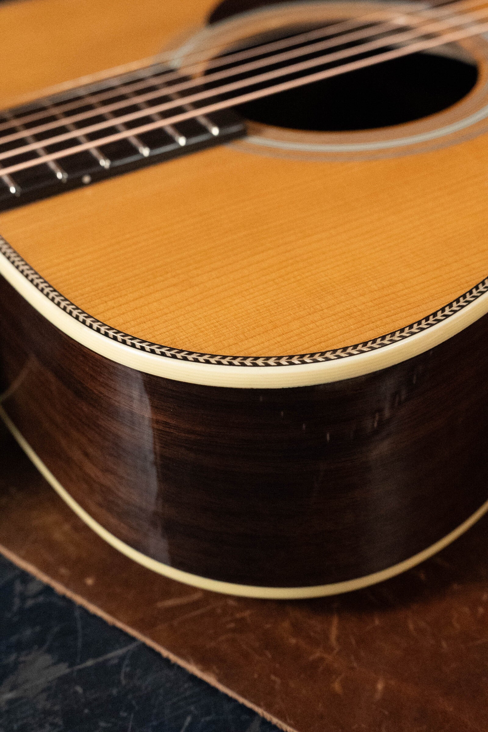 A close-up of the Eastman Guitars E20OM-TC Thermo-Cured Adirondack/Rosewood Orchestra Model Acoustic Guitar #3015 shows its polished body, soundhole, strings, intricate binding, and a glossy finish highlighting the thermo-cured spruce top.