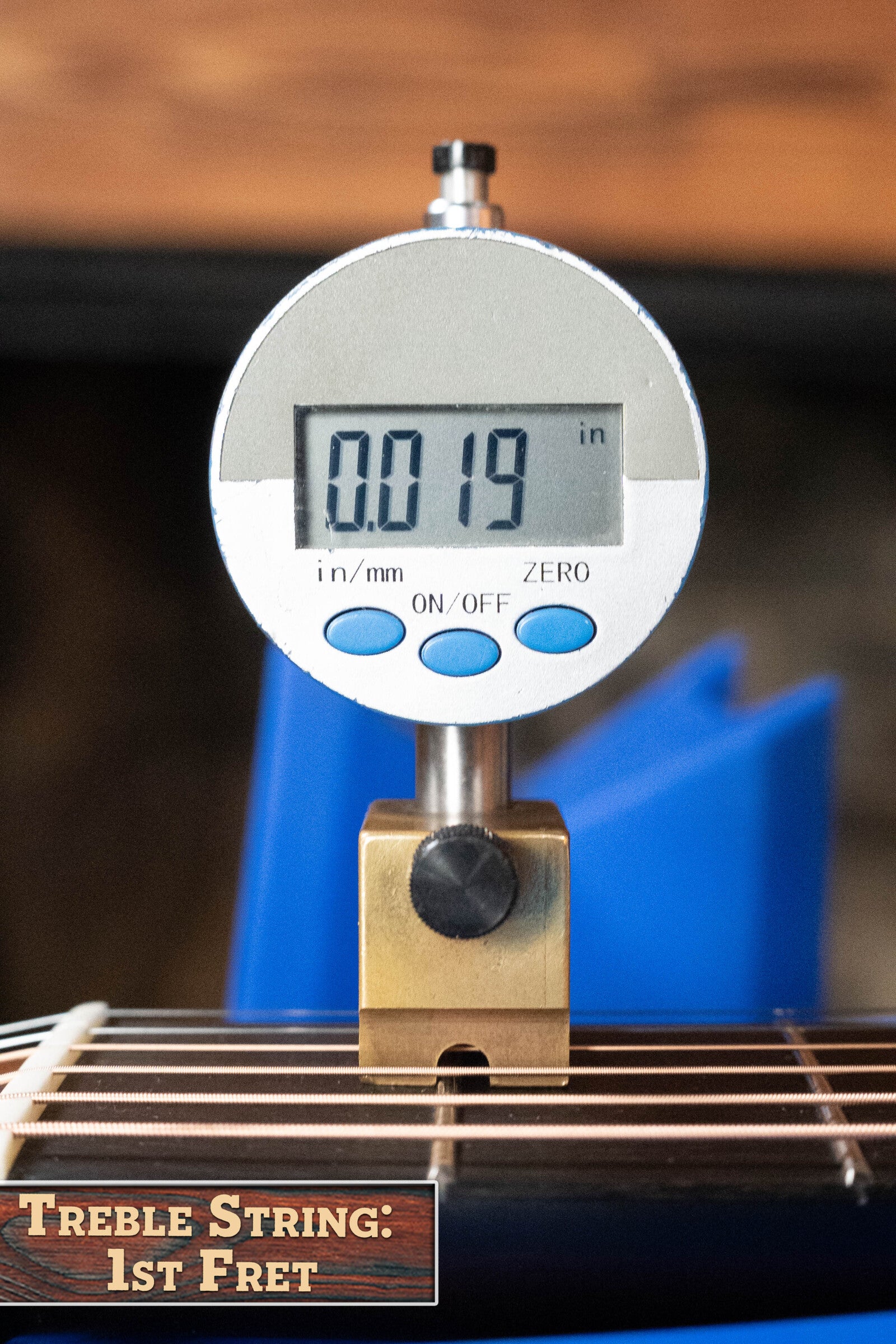 A digital gauge shows 0.019 inches for string height at the first fret of an Eastman E20OM-TC Thermo-Cured Adirondack/Rosewood Orchestra Model Acoustic Guitar #3015. “TREBLE STRING: 1ST FRET” is displayed in the lower left corner.