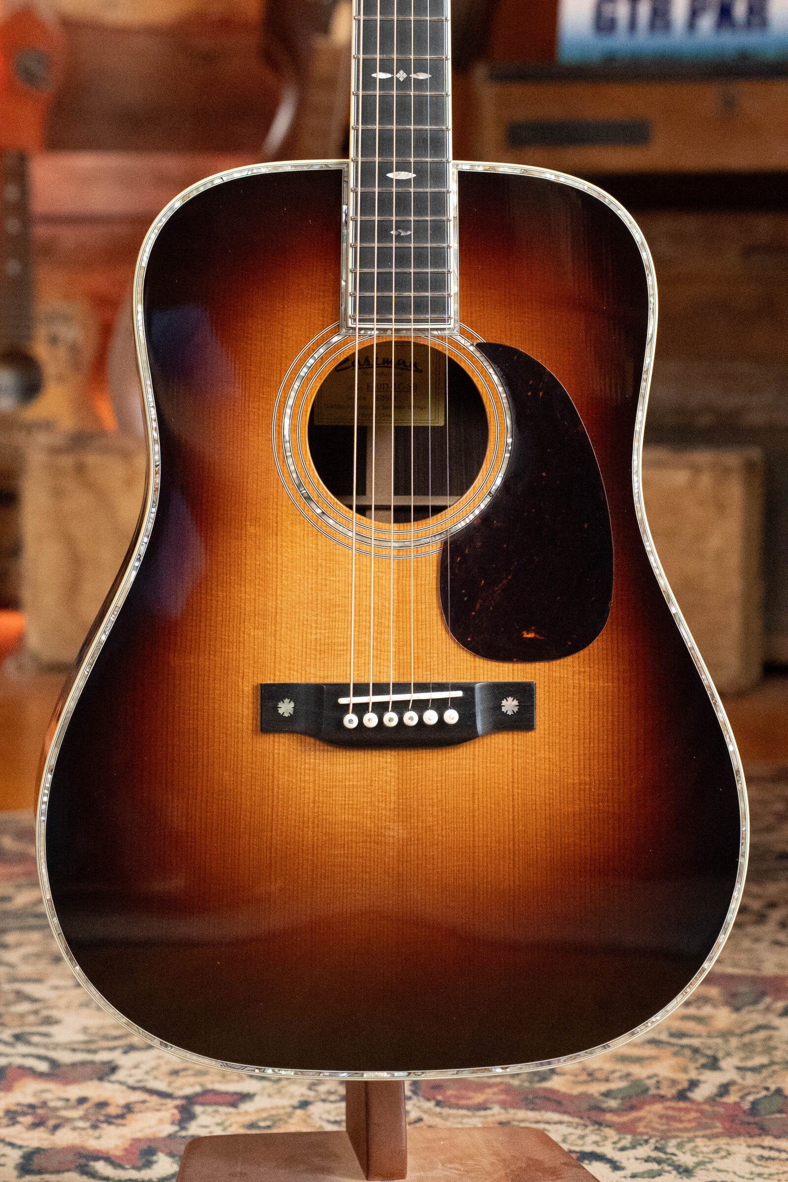 An Eastman Guitars E40D-TC-SB Dreadnought Acoustic Guitar (#1113) with a sunburst finish, thermo-cured AAA Adirondack top, rosewood back and sides, and abalone binding stands upright on a patterned rug.