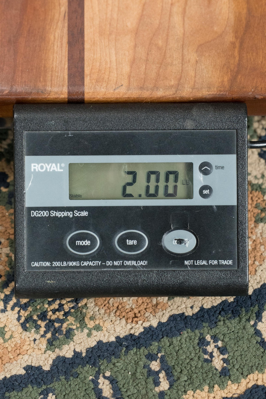 A digital shipping scale on a patterned carpet shows 2.00 pounds as a black Eastman MD314 F-Style Oval Hole Mandolin #4823 by Eastman Guitars, featuring a solid spruce top, rests on it.