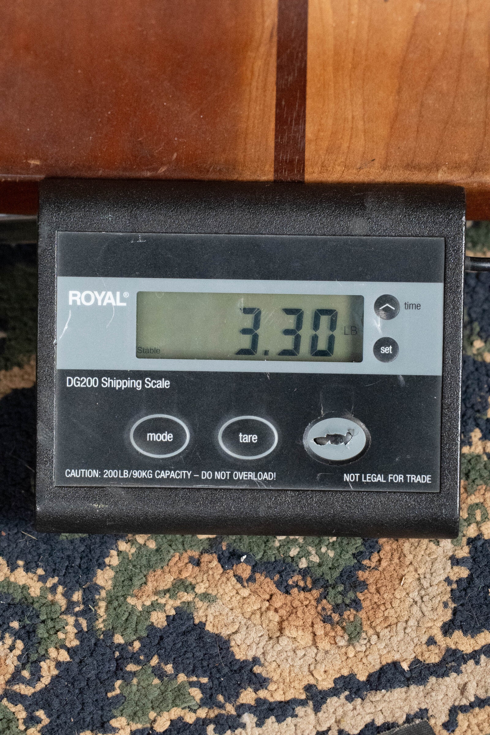 A digital scale on patterned carpet shows 3.30 lbs, weighing part of the Eastman Guitars PCH2-TG Thermo-Cured Solid Sitka/Laminated Rosewood Travel Acoustic Guitar #9714.