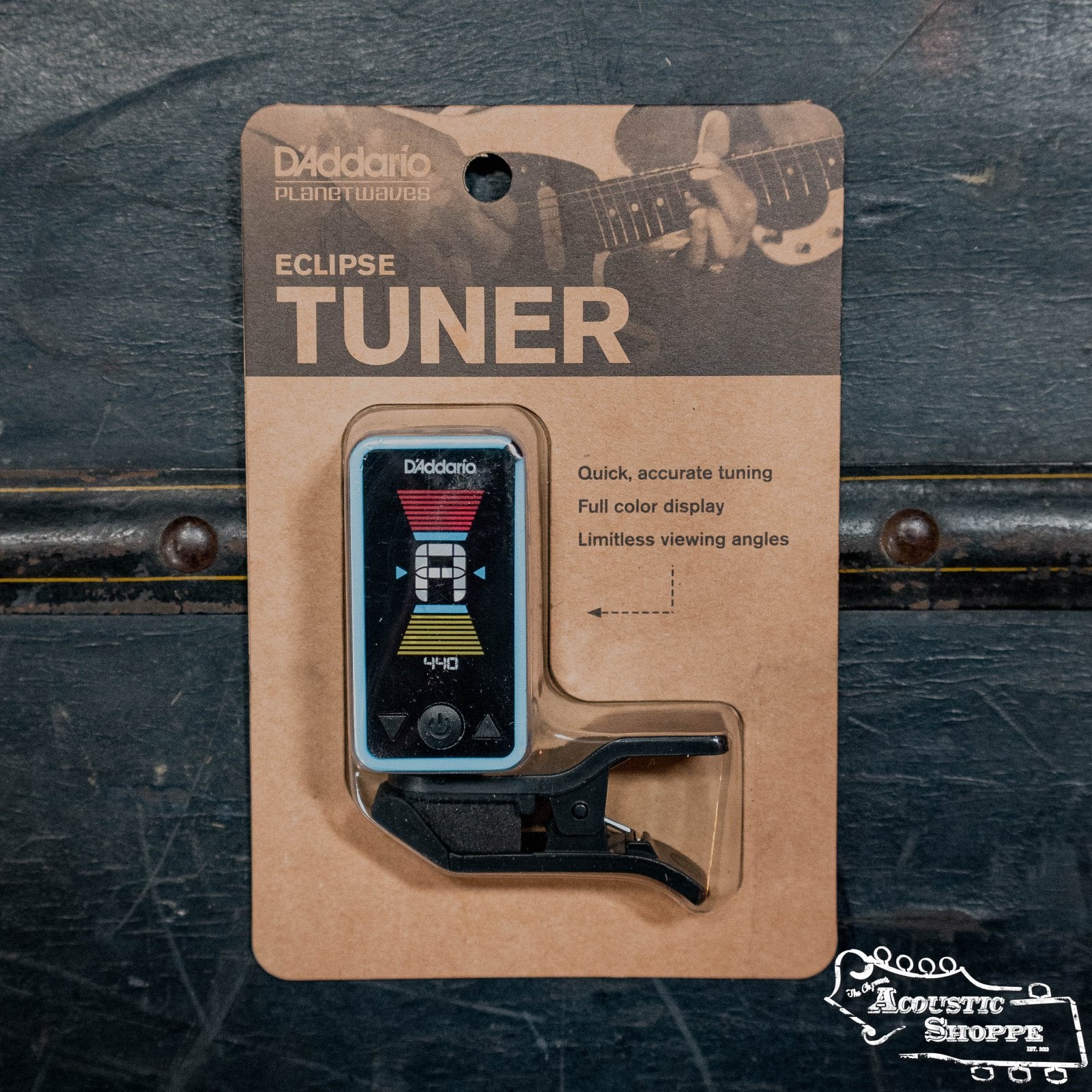 A packaged D'Addario Eclipse Headstock Tuner with a vibrant digital display is shown, set against a background of a guitarist. Packaging highlights include: accurate tuning, full color display, and limitless viewing angles.
