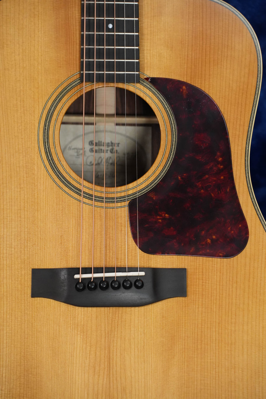 Close-up of the Gallagher Guitar Co. The Bluegrass Bell Dreadnought #4528, featuring torrefied Adirondack spruce top, rosewood back and sides, a dark tortoiseshell pickguard, light amber finish, and visible sound hole label.