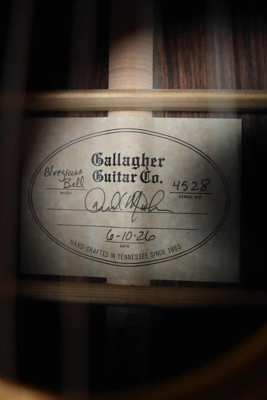 Close-up of a Gallagher Guitar Co. The Bluegrass Bell Torrefied Adirondack/Rosewood Dreadnought (#4528) label—serial 4528, signed and dated 6-10-26, Hand-Crafted in Tennessee since 1965 for rich tone and quality.
