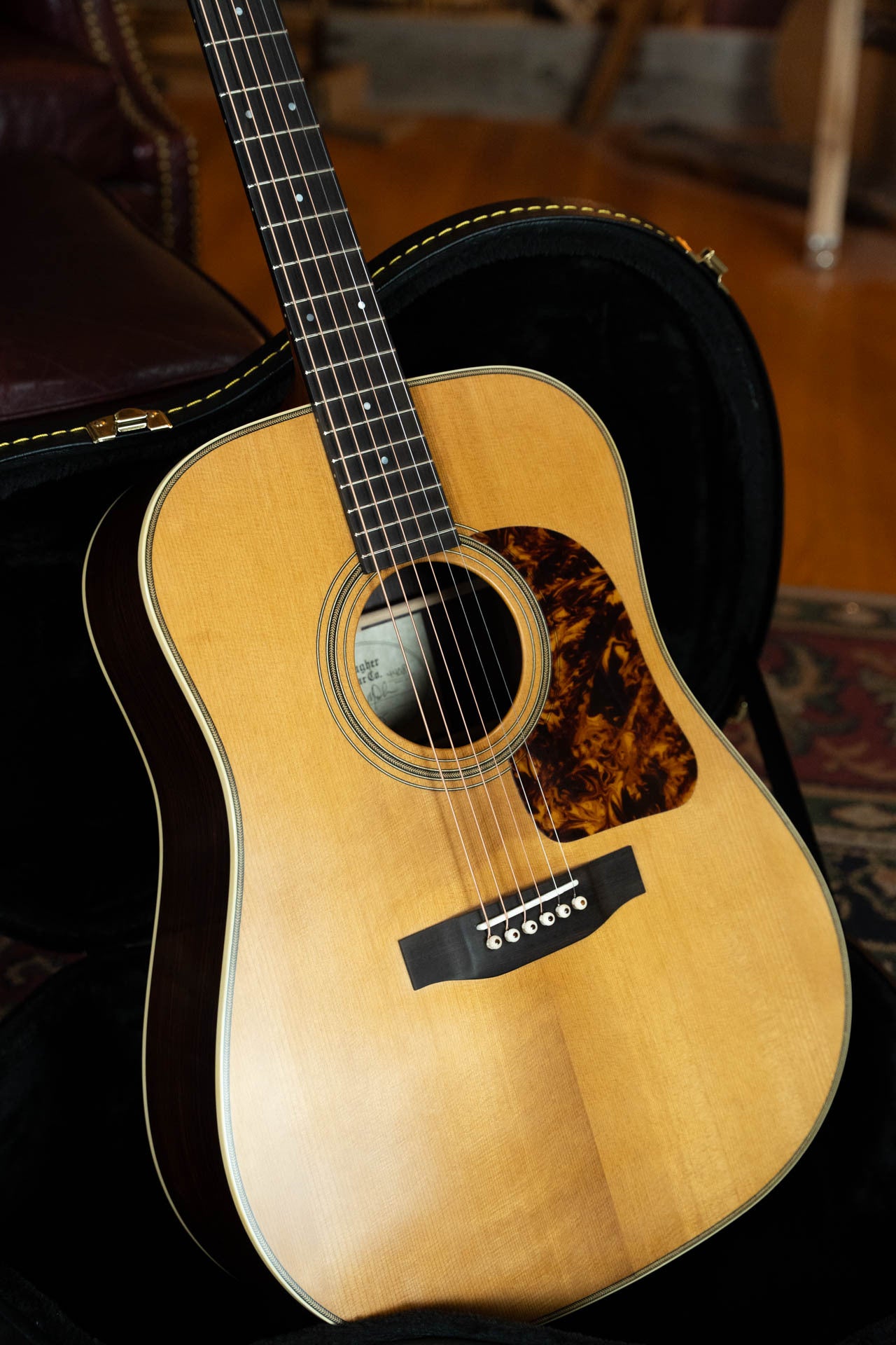 The Gallagher Guitar Co. The Bluegrass Bell Torrefied Adirondack/Rosewood Dreadnought Acoustic Guitar #4408, featuring a natural finish and tortoiseshell pickguard, sits in an open black hard case on a patterned rug.