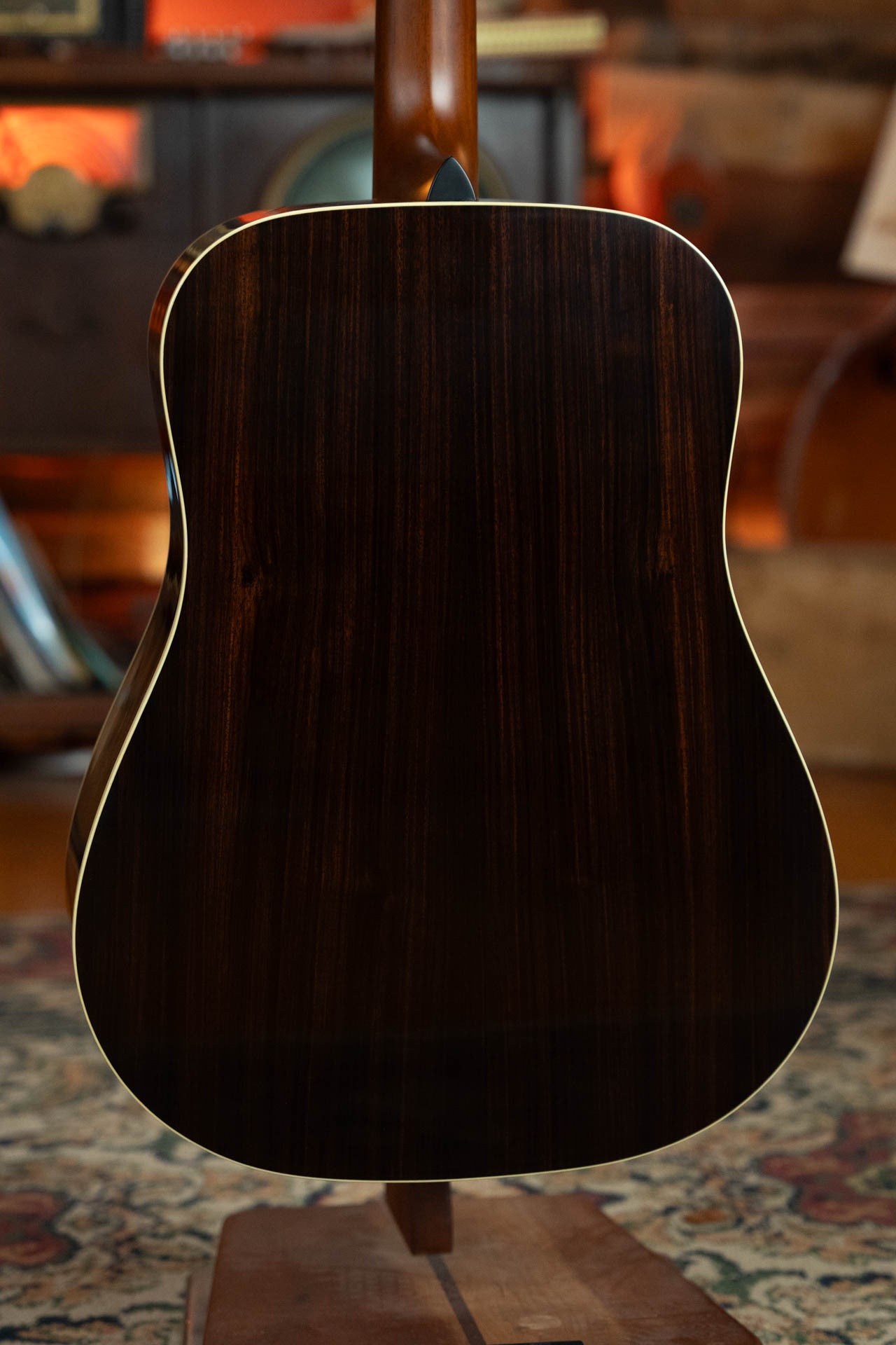 The image displays the back of a Gallagher The Bluegrass Bell Torrefied Adirondack/Rosewood Dreadnought Acoustic Guitar #4408 by Gallagher Guitar Co., featuring a dark rosewood finish with light binding, upright on a stand against warm, vintage decor.