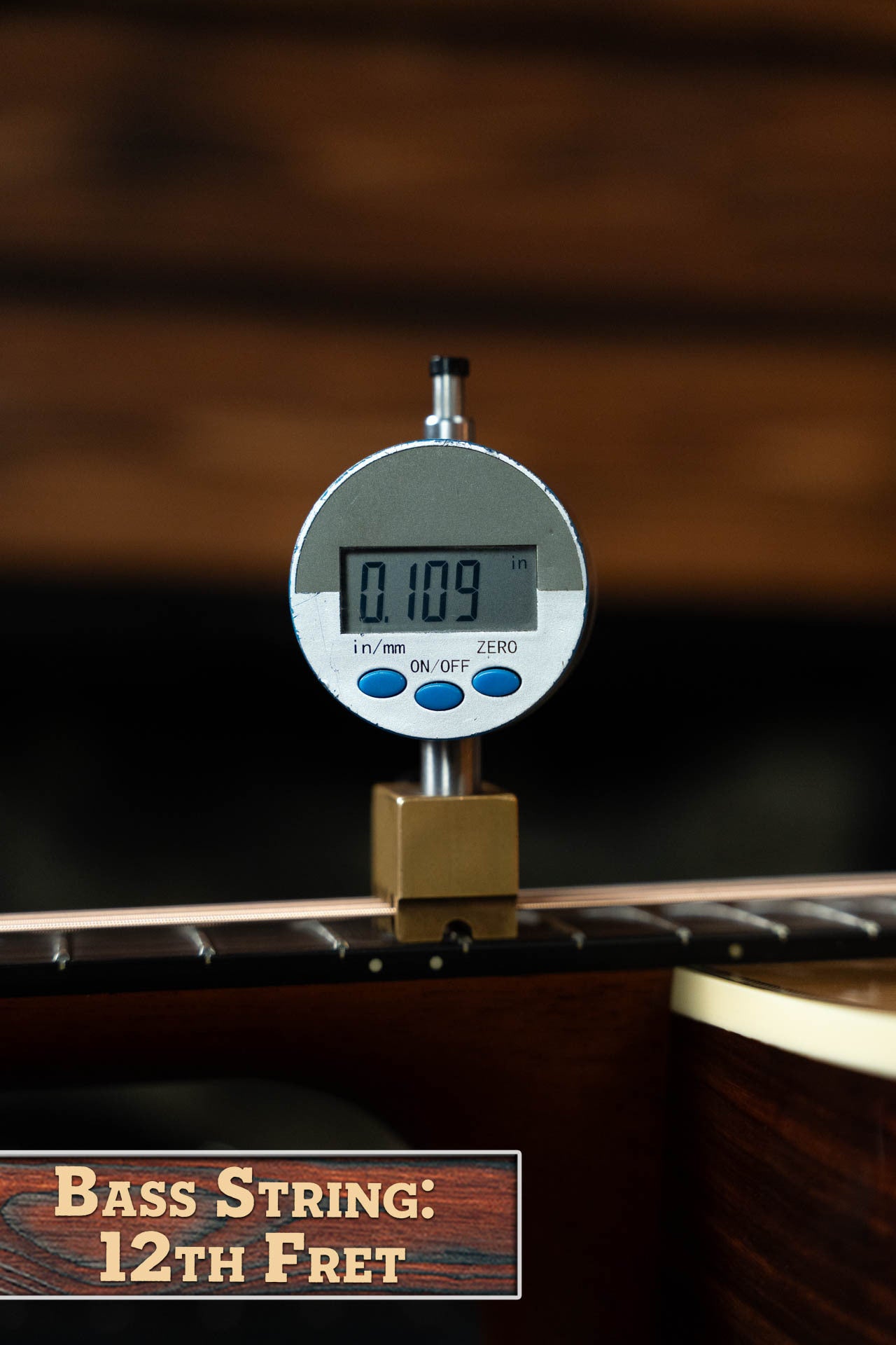 A digital gauge shows 0.109" on the bass string at the 12th fret of the Gallagher The Bluegrass Bell Torrefied Adirondack/Rosewood Dreadnought Acoustic Guitar #4408 by Gallagher Guitar Co., set against a blurred wood background evoking quality craftsmanship.