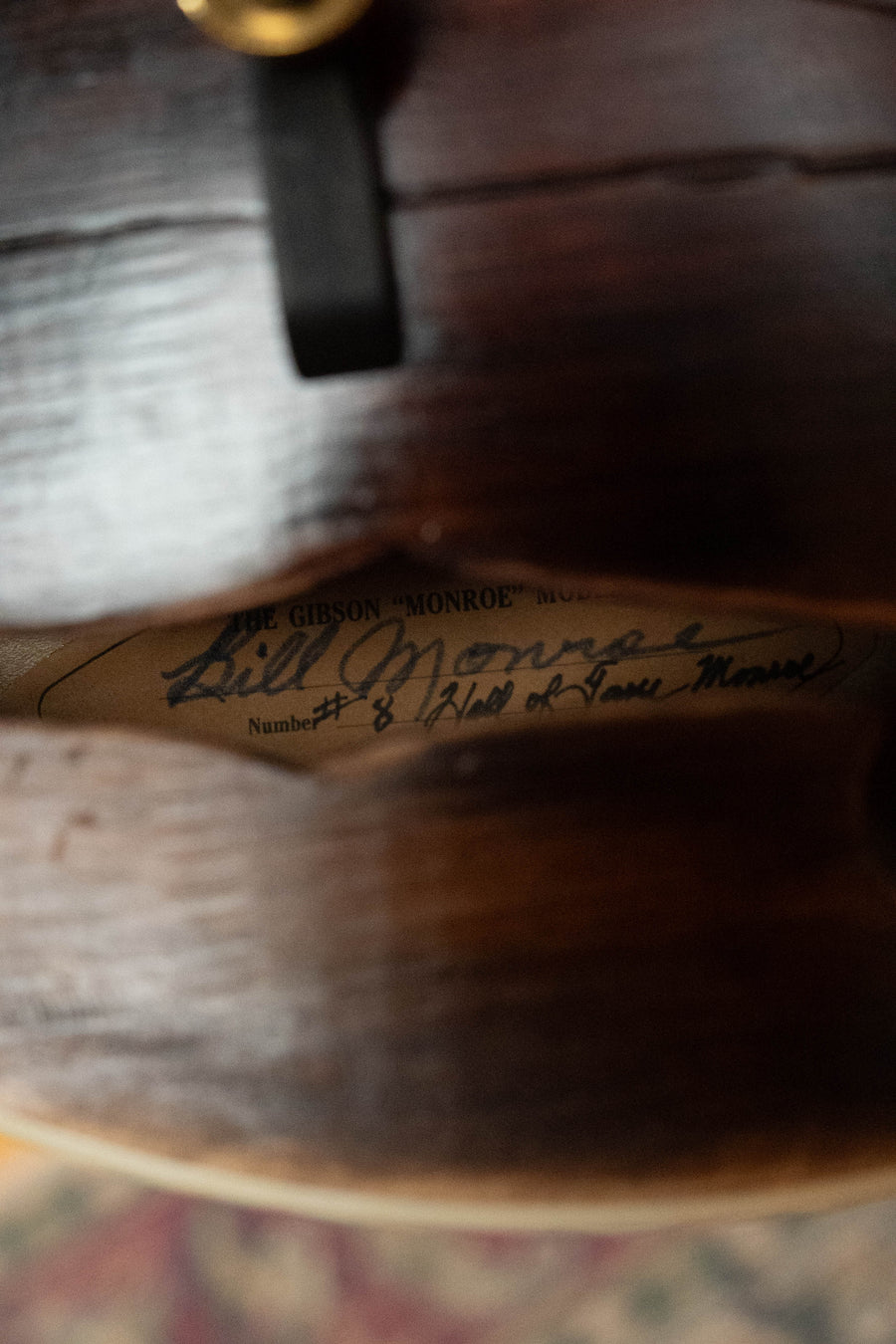 Close-up of the inside of a Gibson F-5 Hall of Fame Monroe Cremona Burst Mandolin GH, showing a handwritten label reading “Gibson ‘Monroe’ Model, Bill Monroe, Number 8 ‘Head of Lone Moose’.”.