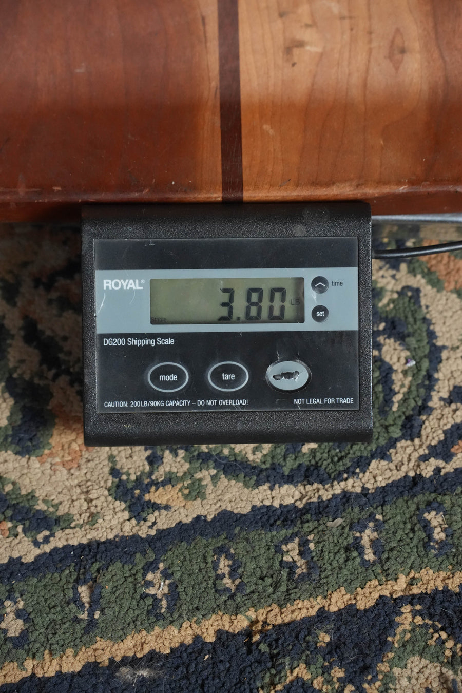 A ROYAL DG3200 Shipping Scale on a patterned rug shows 3.80 lbs, possibly weighing the Guild M-20 Natural All African Mahogany Concert Acoustic Guitar #0317 by Guild Guitars. The scale features various buttons and a caution label.