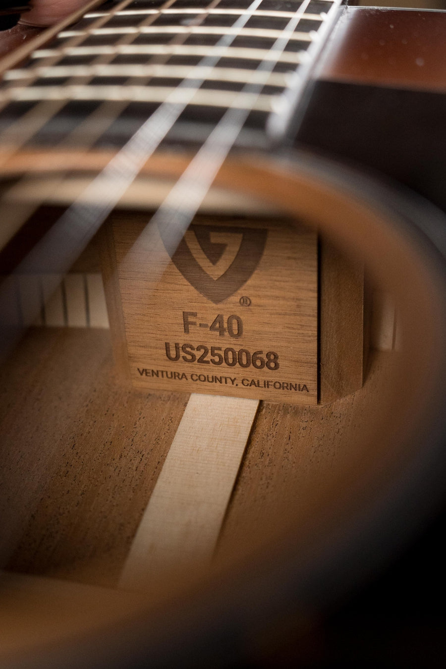 Close-up view through the sound hole of a Guild Guitars F-40 Standard Sitka/Mahogany Pacific Sunset Burst Jumbo Acoustic Guitar (#0068), showing its label inside.