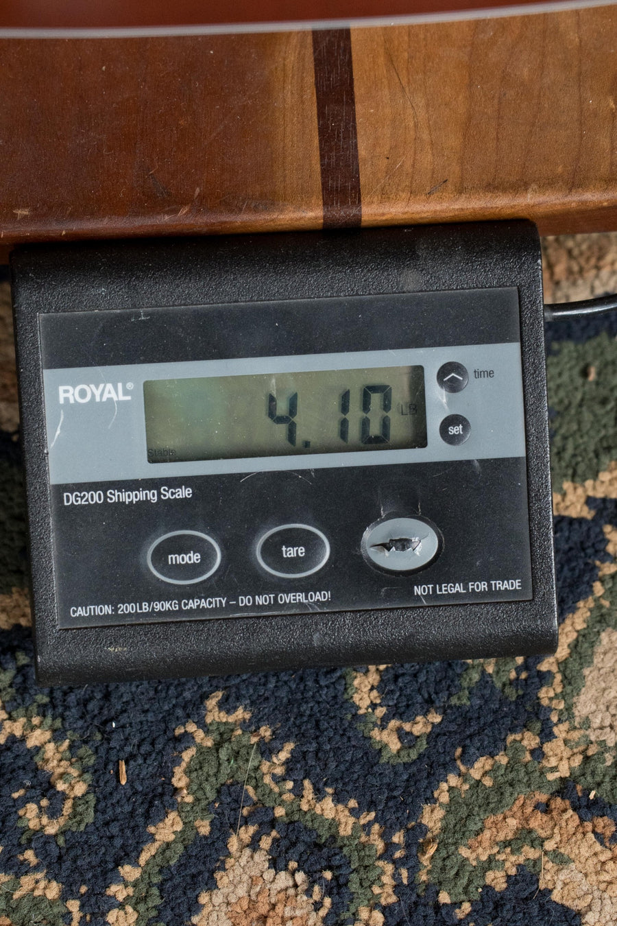 A digital shipping scale shows 4.10 pounds with a partial view of a Guild F-40 Standard Sitka/Mahogany Pacific Sunset Burst Jumbo Acoustic Guitar (#0068) from Guild Guitars resting on it.