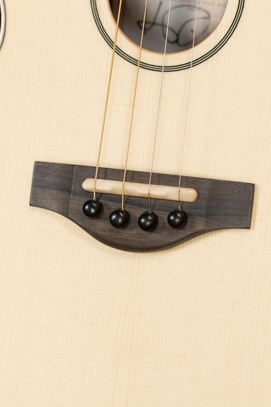 Close-up of spruce top acoustic mandolindo bridge with rosewood base and four black bridge pins holding brass strings. - KR Strings Artist Spruce/Rosewood Acoustic Mandolindo #0001 - Default Title