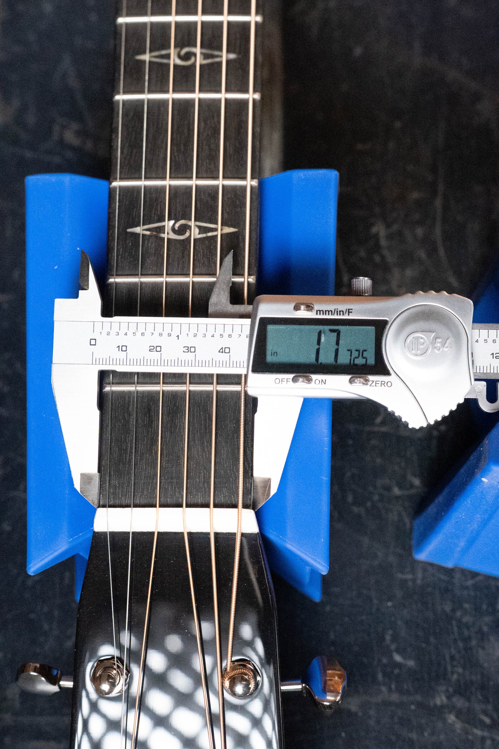 A digital caliper measures the width of a Martin & Co. *Limited Edition* CEO-11 European Spruce/White Oak New Horizons Blue Burst Grand Auditorium Guitar neck at 47.25 mm, held in blue supports. The display and guitar strings are clearly visible.