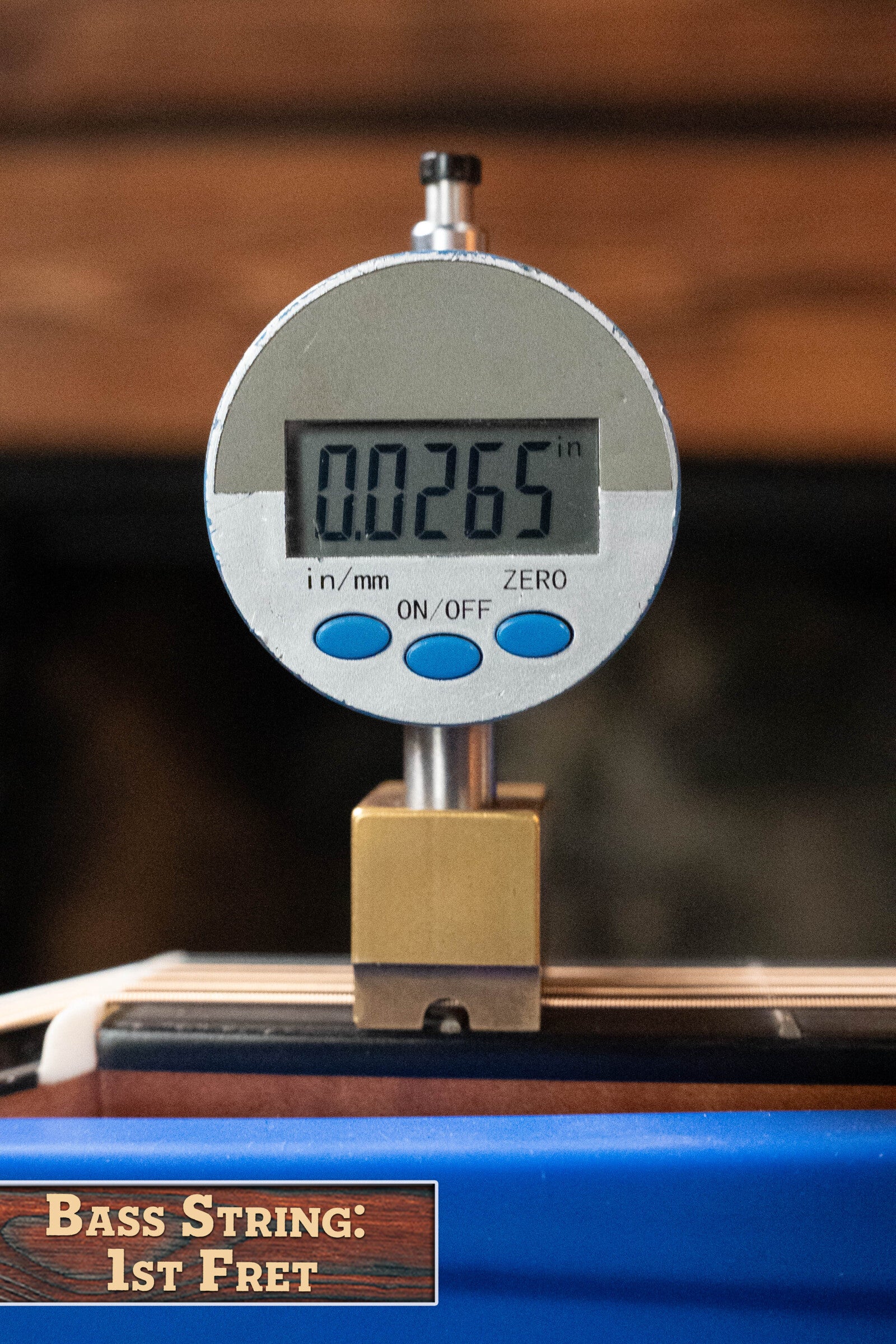 A digital gauge shows 0.0265 inches, measuring the string height at the 1st fret. A corner label reads: Bass String: 1st Fret, evoking the limited edition style of Martin & Co.’s CEO-11 New Horizons Blue Burst Guitar #1204.