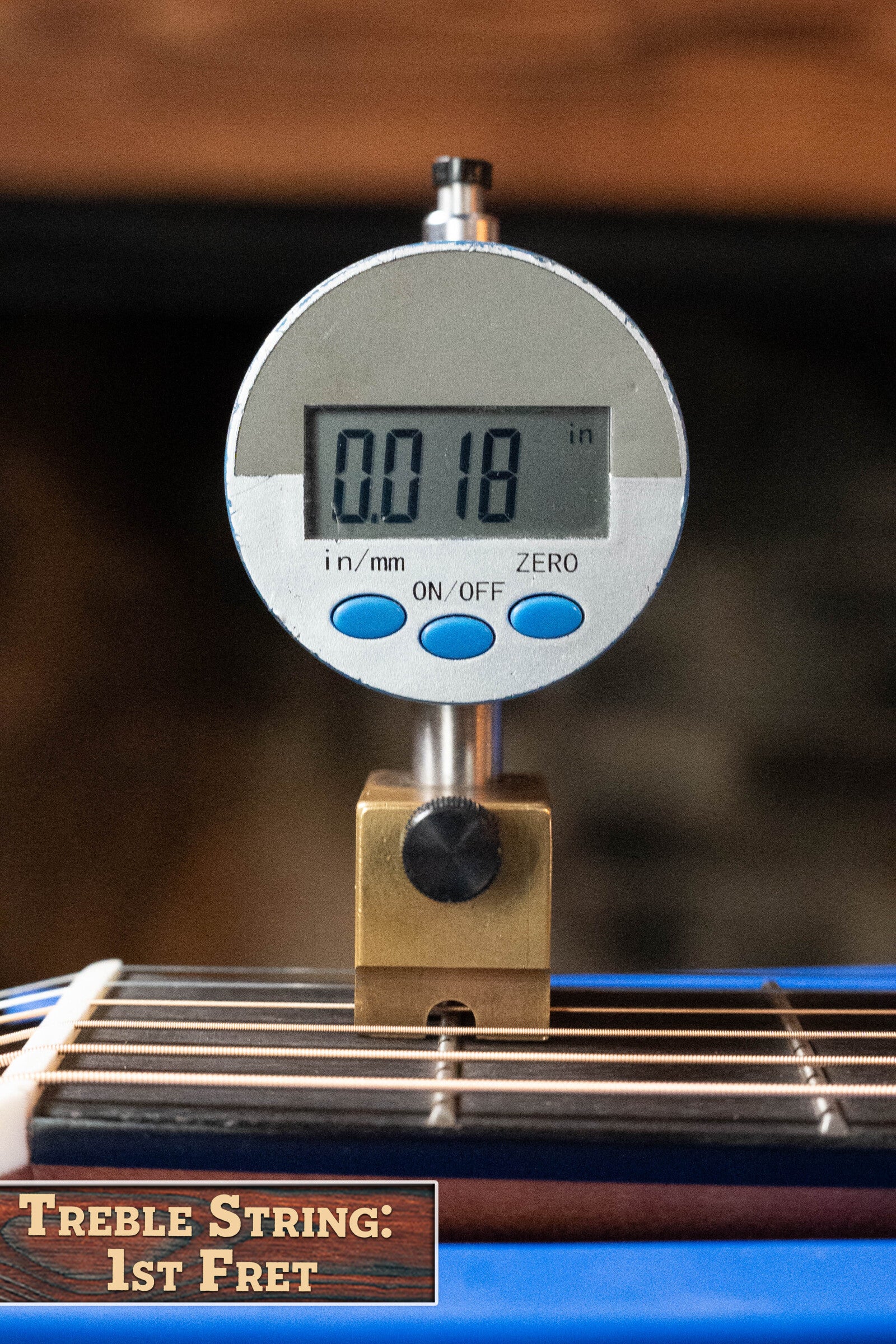 A digital gauge reads 0.018 inches at the 1st fret treble string of a *Limited Edition* Martin & Co. CEO-11 European Spruce/White Oak New Horizons Blue Burst Grand Auditorium Guitar w/Electronics #1204.
