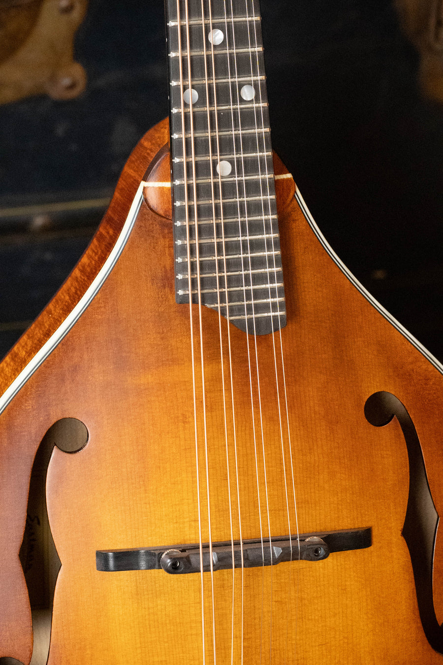 Close-up of the PRE-ORDER DEPOSIT ONLY *New 2026 Model* Eastman MD305 Wide Nut Adirondack/Maple A-Style Mandolin by Eastman Guitars, featuring a warm brown wooden body, strings, f-shaped sound holes, and white edge trim.