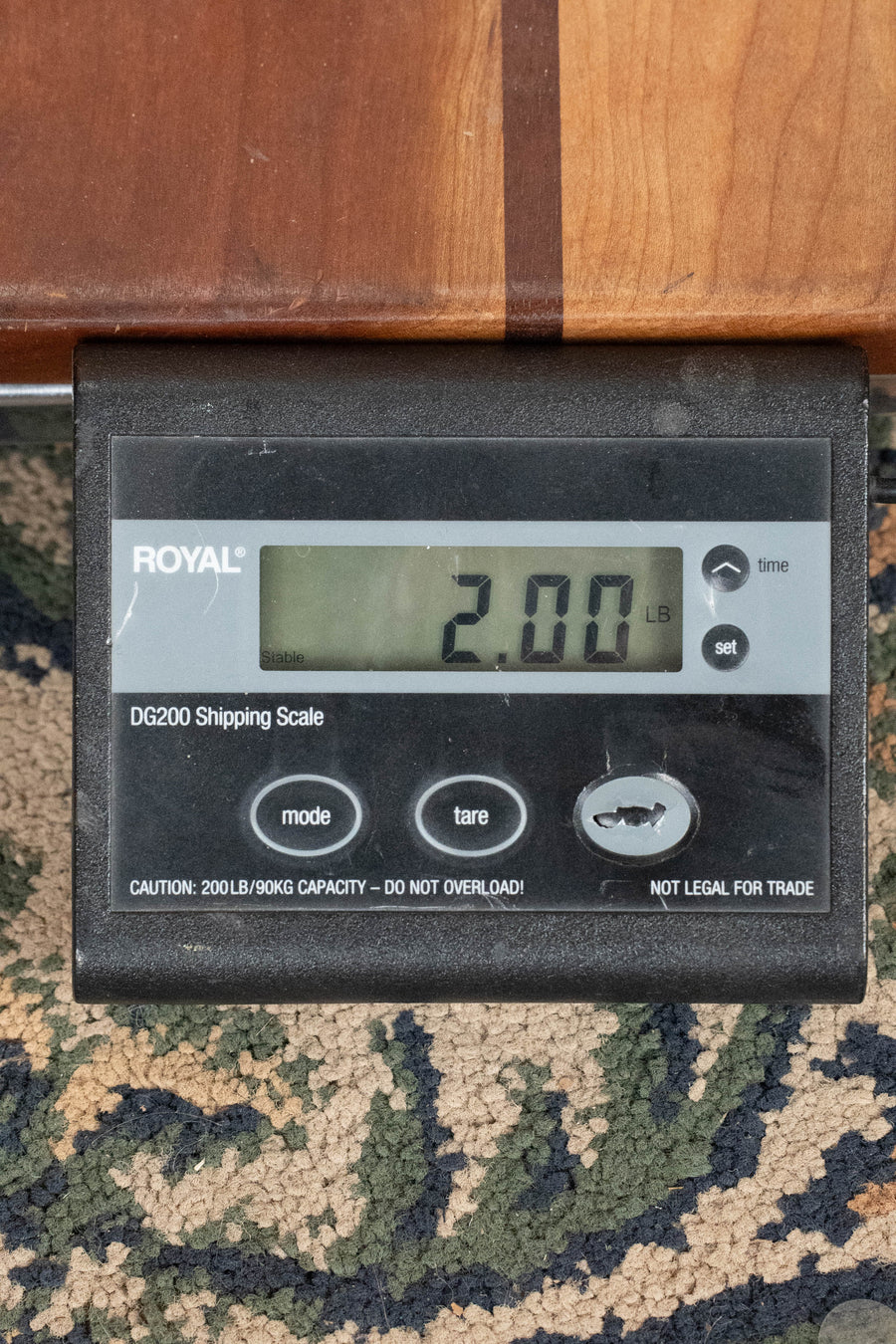 A digital shipping scale reads 2.00 pounds as the black ROYAL DG200 sits on patterned carpet, weighing an Eastman Guitars PRE-ORDER DEPOSIT ONLY *New 2026 Model* MD305 Wide Nut Adirondack/Maple A-Style Mandolin before shipping.