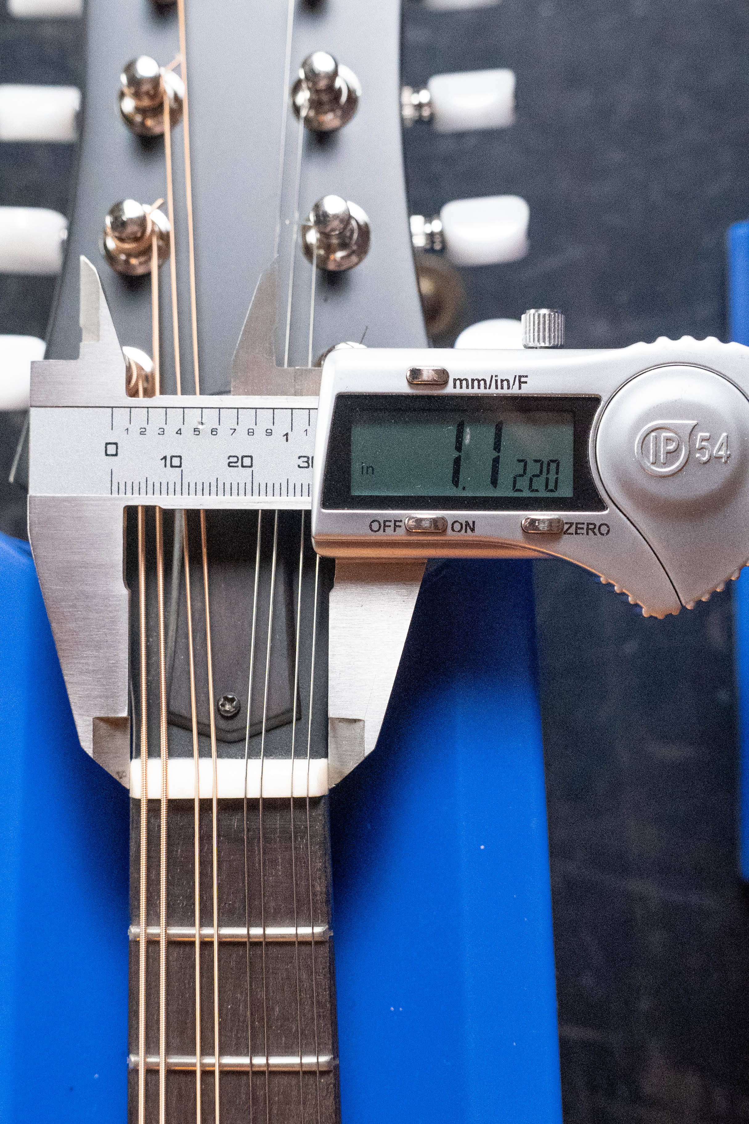 A digital caliper shows 1.1220 inches string spacing on an Eastman MD305 Spruce/Maple A-Style Hand-Carved Mandolin #3317 by Eastman Guitars, with its solid spruce top resting on a blue stand.