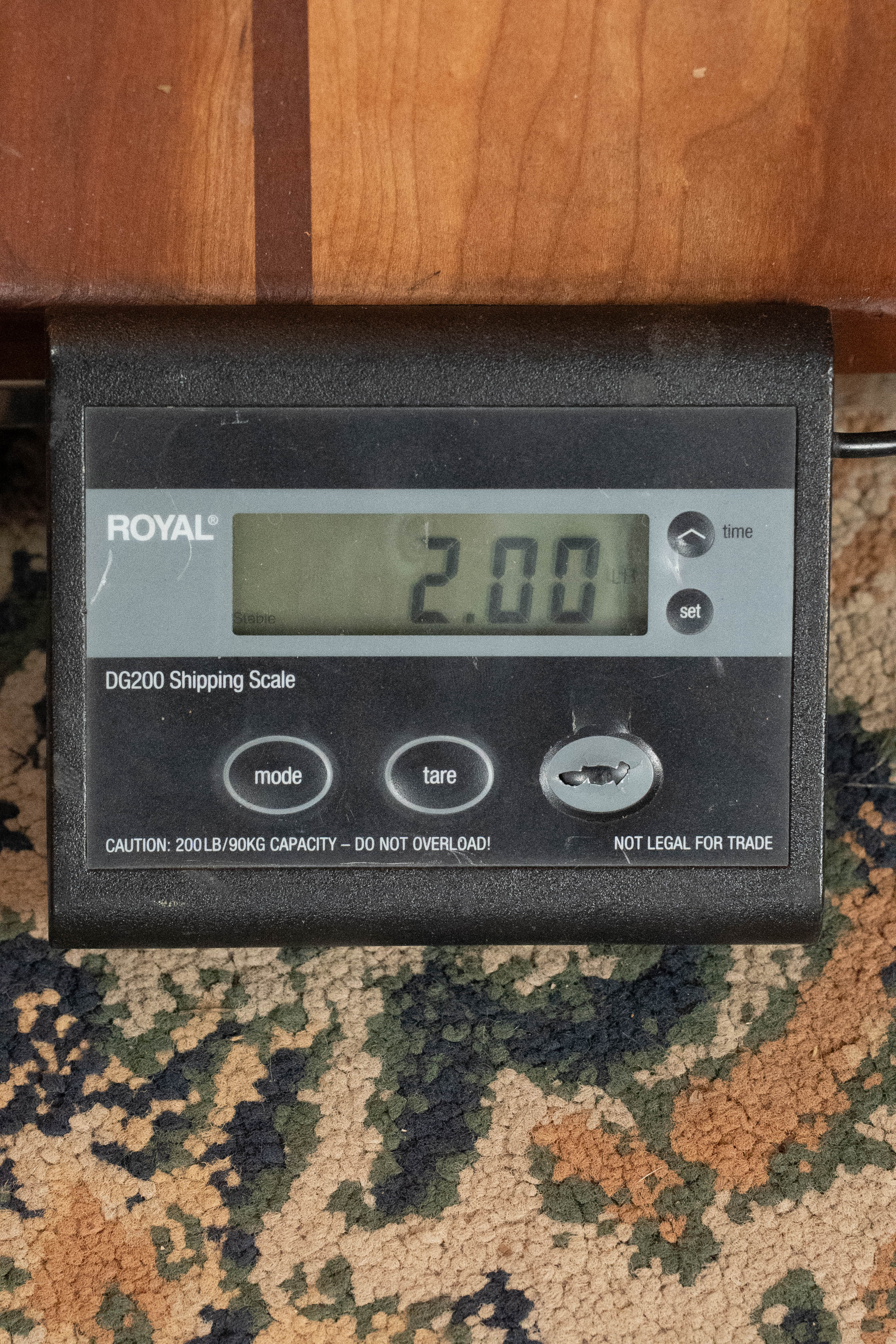 A digital shipping scale displays 2.00 while on a patterned carpet, with part of an Eastman MD305 Spruce/Maple A-Style Hand-Carved Mandolin (#3317) by Eastman Guitars visible above the scale.