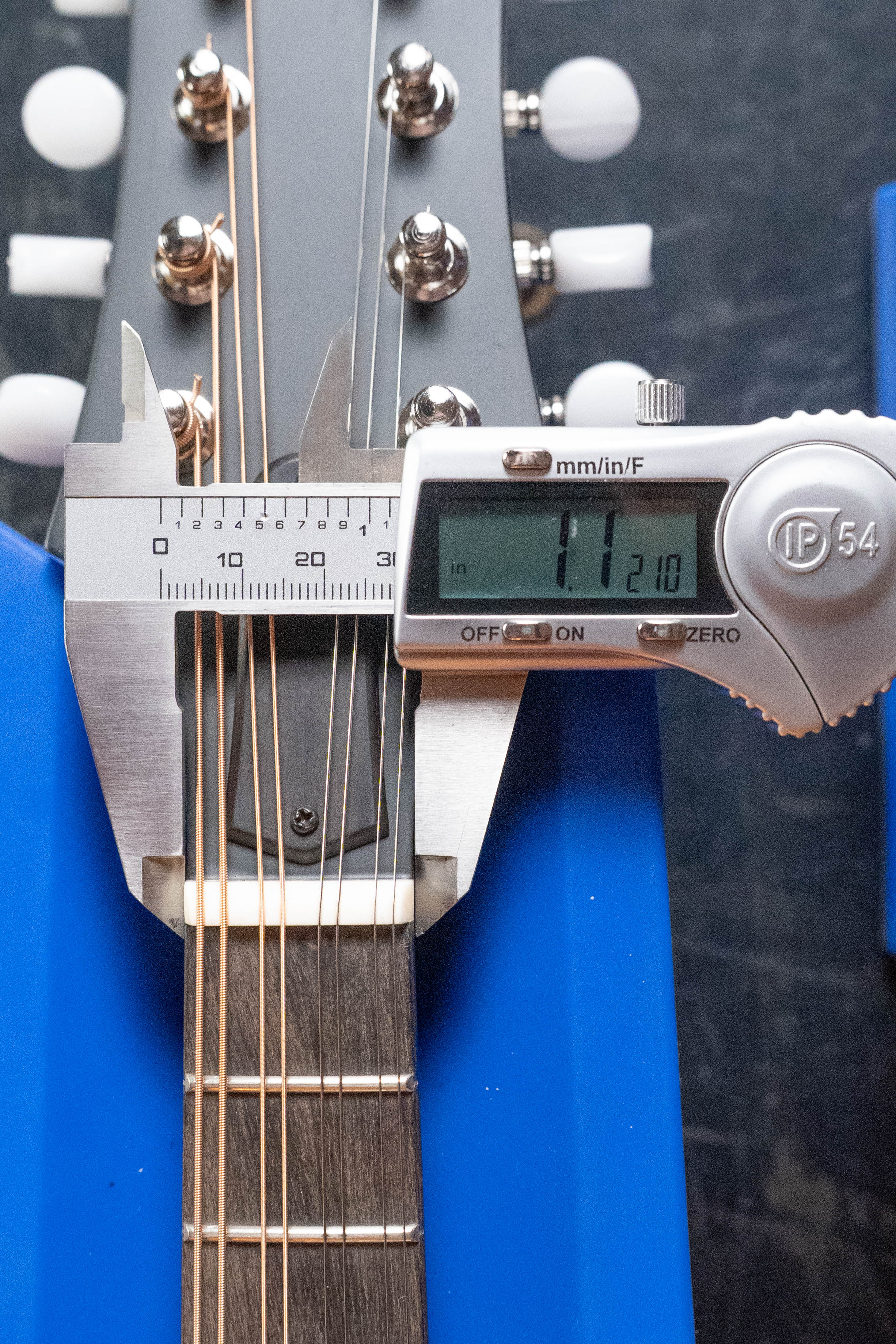 A digital caliper shows the nut width of 1.7210” on an Eastman Guitars MD305 Spruce/Maple A-Style Hand-Carved Mandolin #3596, with all 8 strings visible as it rests in a blue holder—ideal for checking mandolin specs.
