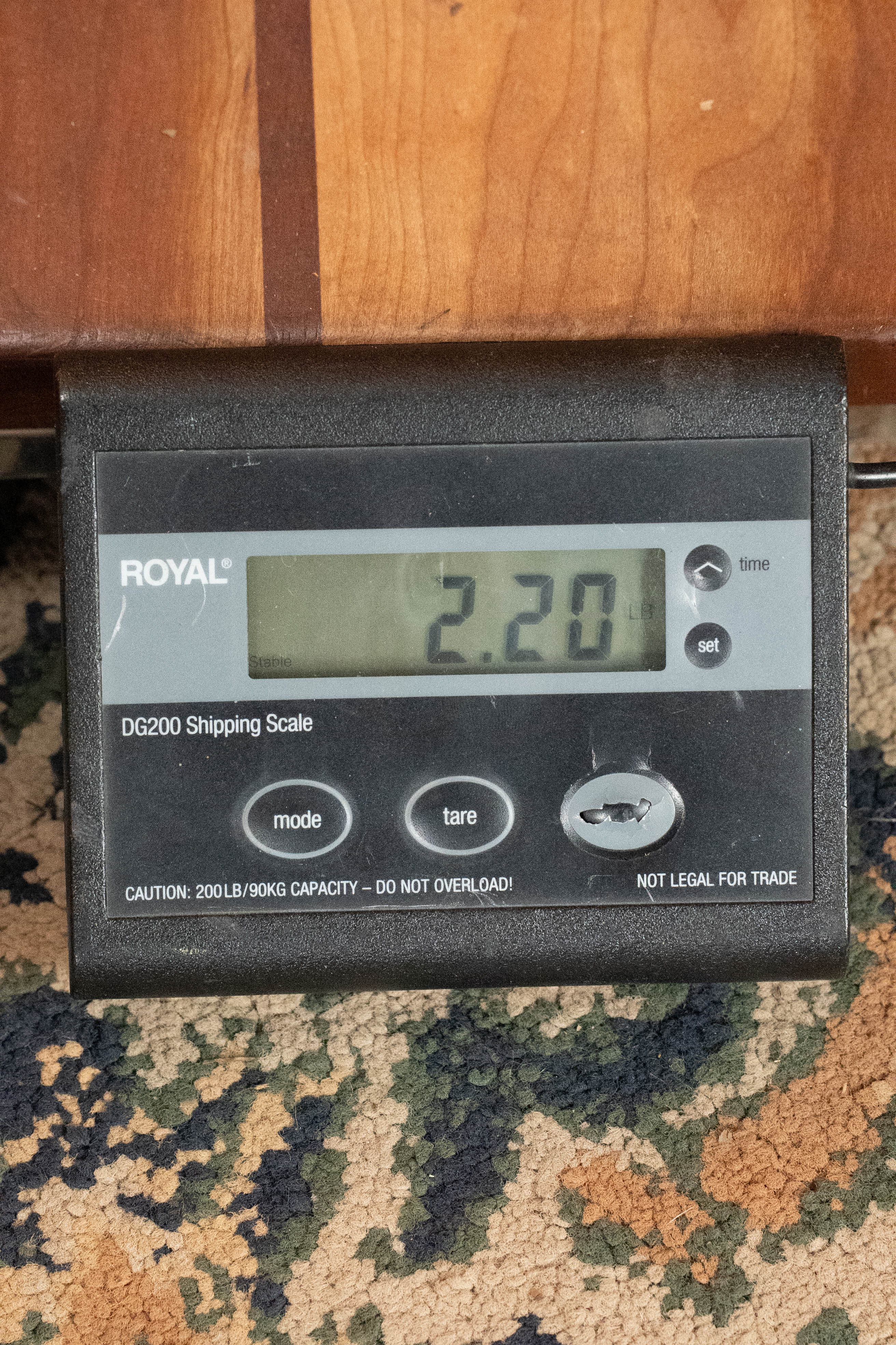 A digital shipping scale shows 2.20 pounds on a patterned carpet, with part of an Eastman Guitars MD315 F-Style Hand-Carved Mandolin (#0917) visible above.