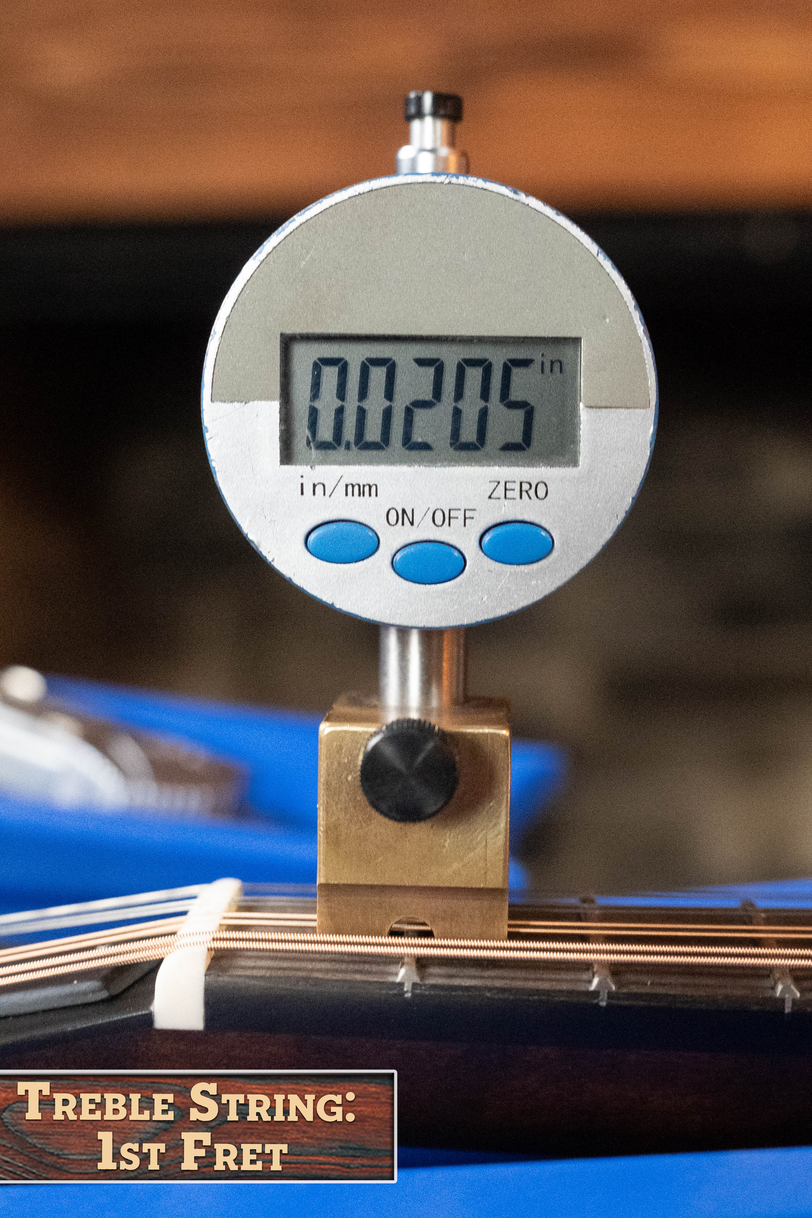 A digital gauge shows 0.0205 inches as it measures the treble string height above the 1st fret on an Eastman MD315 F-Style Hand-Carved Mandolin (#0917) by Eastman Guitars. A label reads, Treble String: 1st Fret.