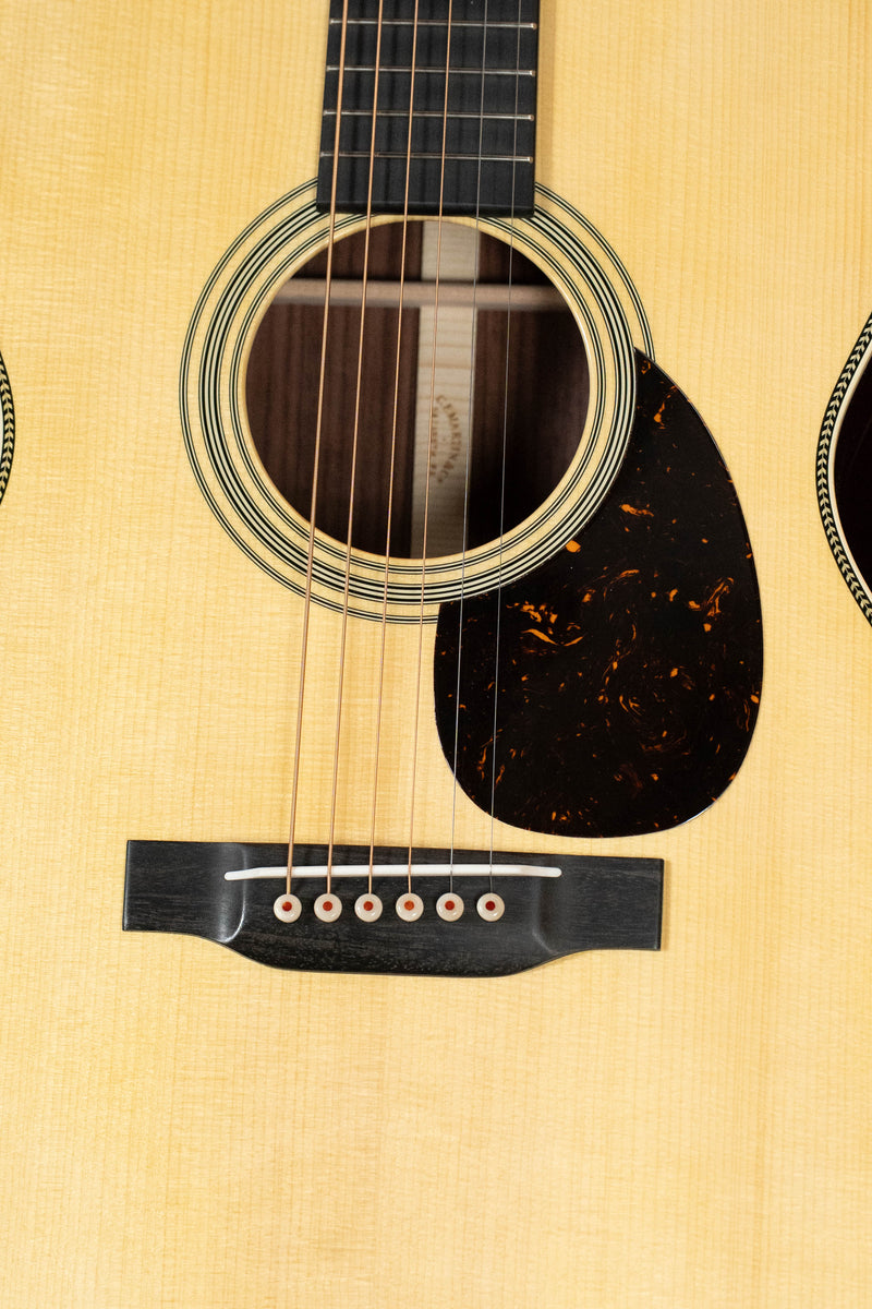 Martin Custom Shop OM-28-Style: front view showing spruce top, rosette, pickguard, and bridge with pins.