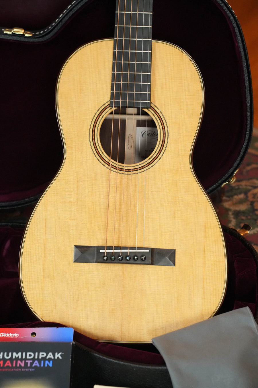 The Martin & Co. Custom Shop Sitka/Rosewood Acoustic Guitar #6904, with a VTS Sitka spruce top and light wood body, is displayed in an open hard case; DAddario Humidipak Maintain packaging and a gray cloth are nearby.