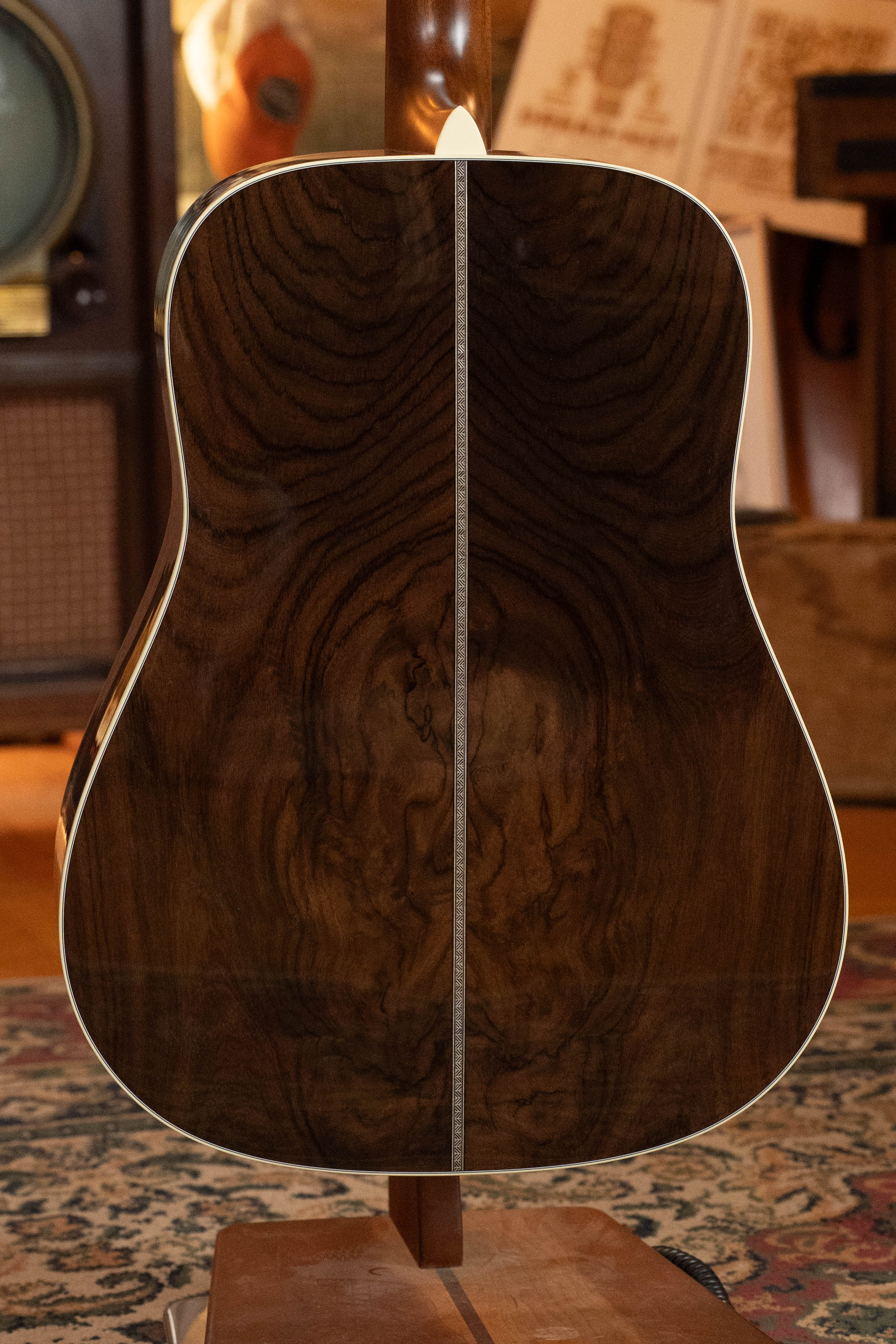 The image shows the back of a Martin & Co. Custom Shop HD-28 Style Spruce/Wild Grain Rosewood Custom "D" Dreadnought Acoustic Guitar #7410, highlighting its striking wood grain and central decorative strip in warm lighting.