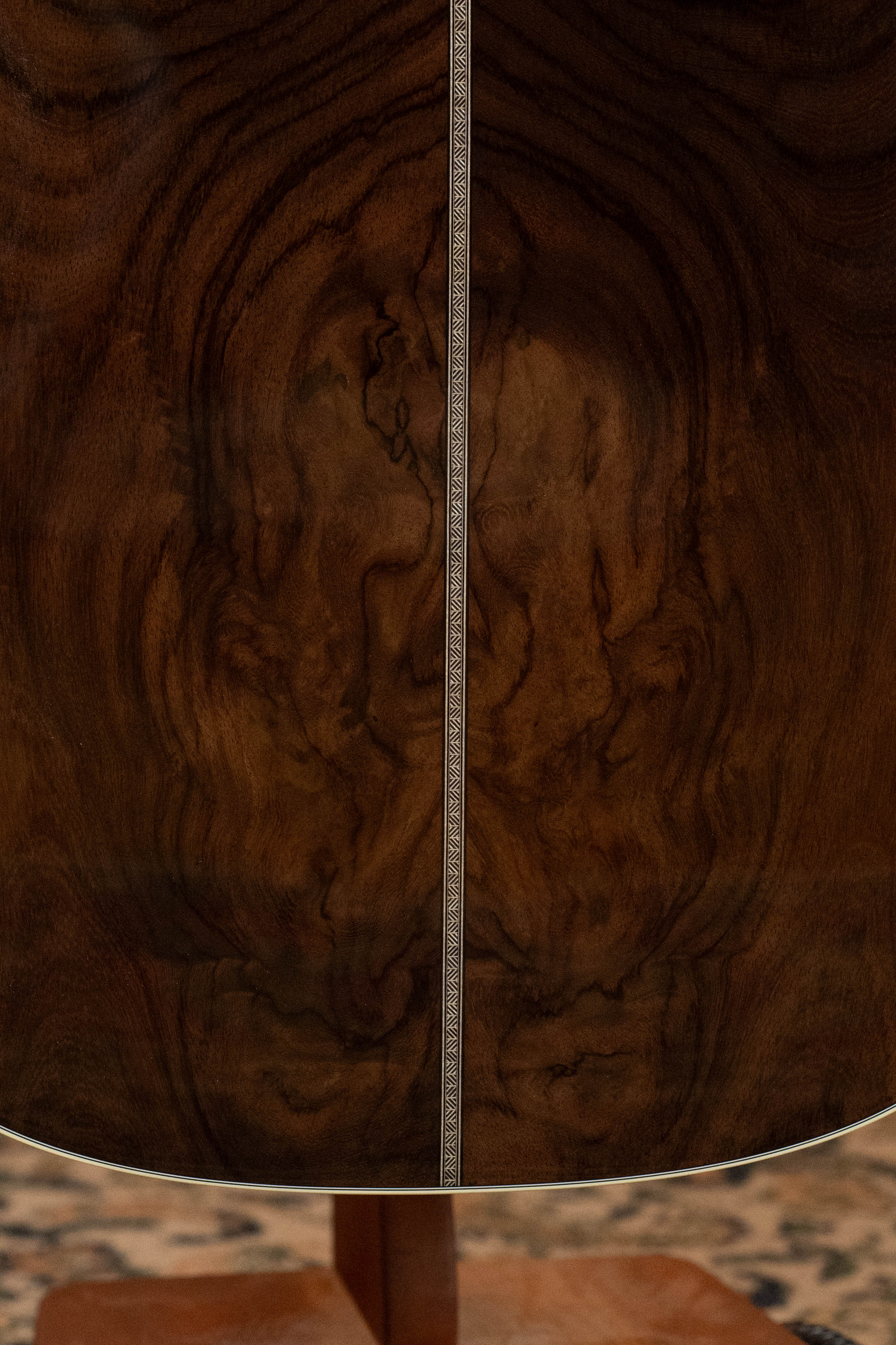 The image shows the back of a Martin & Co. Custom Shop HD-28 Style Spruce/Wild Grain Rosewood Custom "D" Dreadnought Acoustic Guitar #7410 with dark, richly grained wood and a center inlay strip, set against a patterned carpet background.