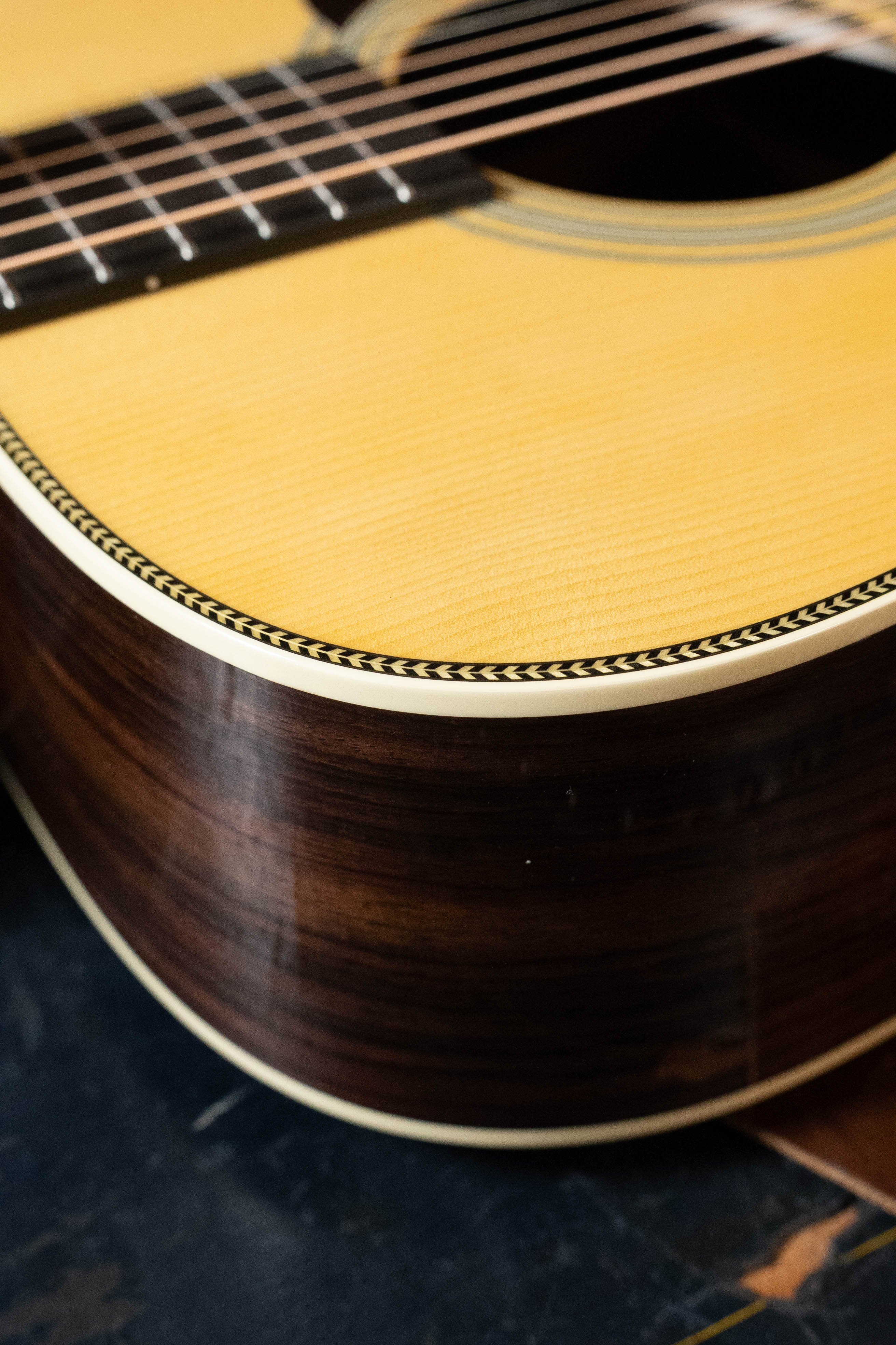 Close-up of the Martin & Co. Custom Shop HD-28 Style Spruce/Wild Grain Rosewood Custom "D" Dreadnought Acoustic Guitar #7410, highlighting its Adirondack spruce top, wild grain rosewood sides, edge binding, and fretboard.