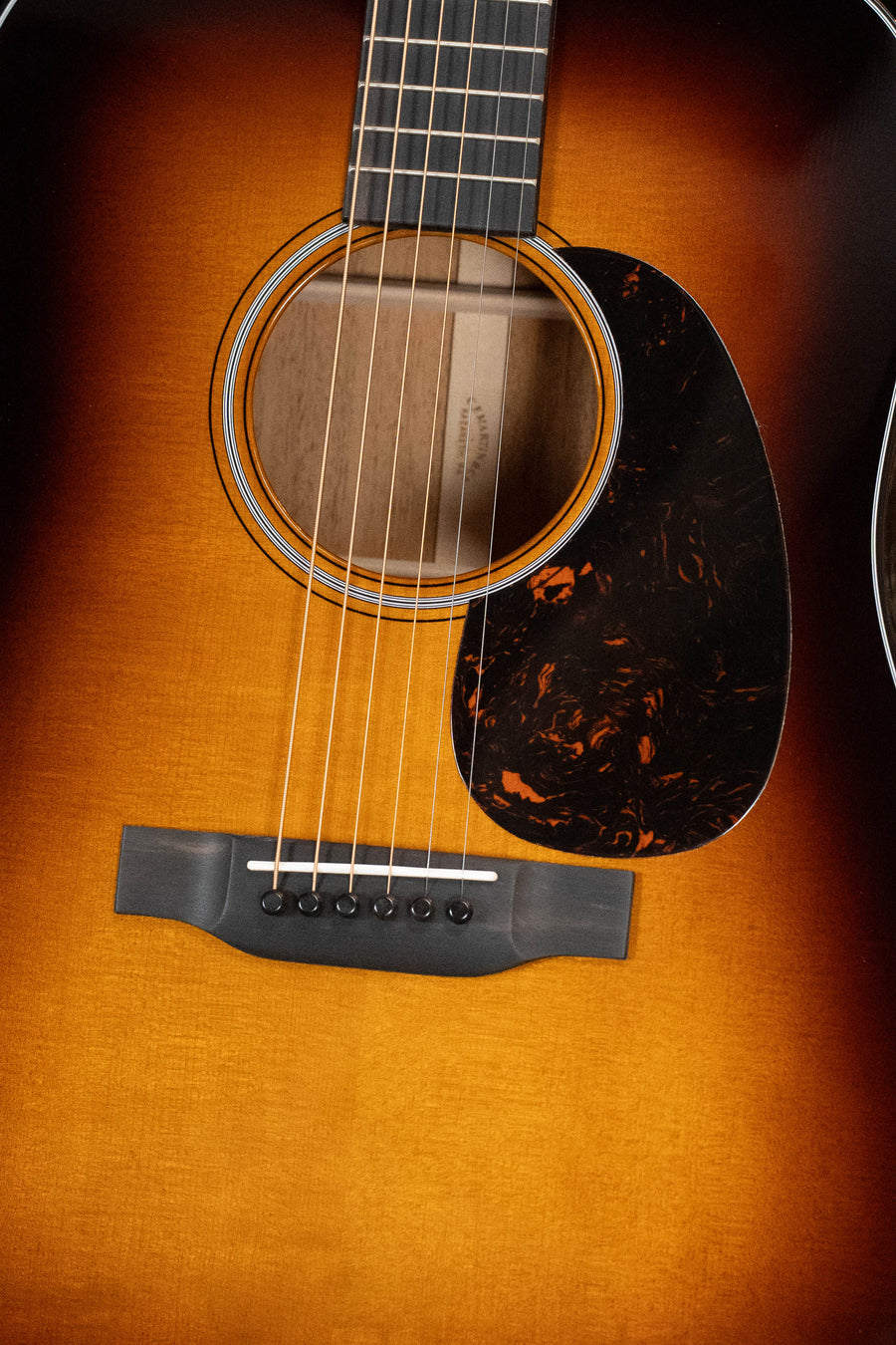 Close-up of a Martin & Co. D-18 Spruce/Mahogany 1935 Gloss Sunburst Finish Dreadnought Acoustic Guitar #5454, highlighting the strings, soundhole, pickguard, and part of the fretboard.