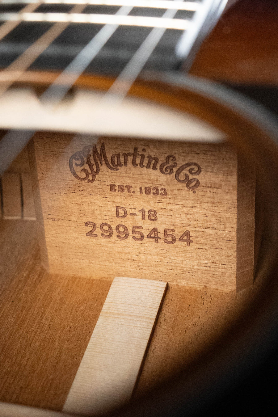 A close-up through the sound hole of the Martin & Co. D-18 Spruce/Mahogany 1935 Gloss Sunburst Dreadnought Acoustic Guitar #5454 shows a wooden label engraved with "C.F. Martin & Co. EST. 1833, D-18, 2995454.