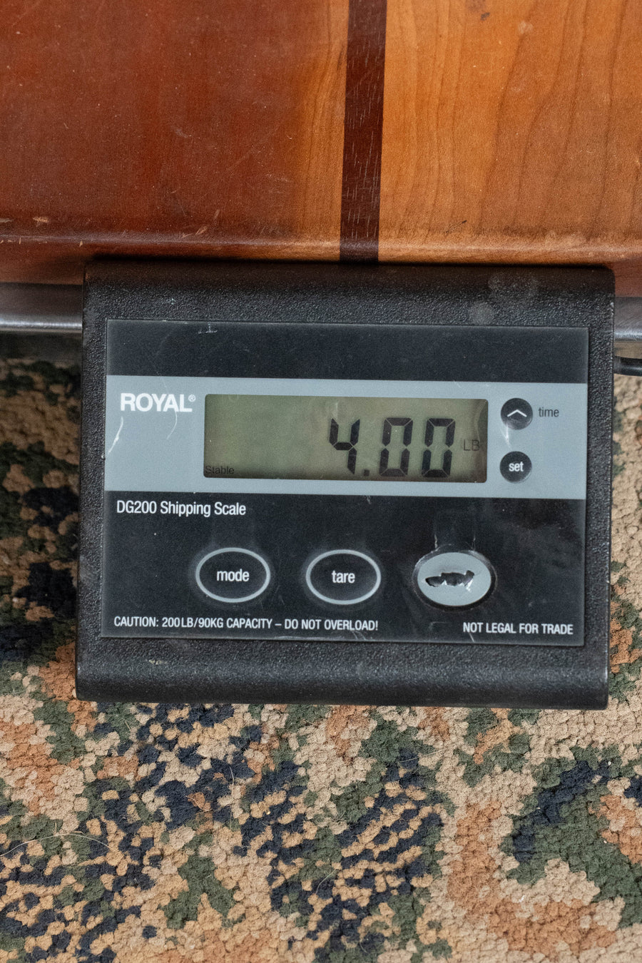 A digital shipping scale on a patterned carpet shows a weight of 4.00 pounds with part of a Martin & Co. D-18 Spruce/Mahogany 1935 Gloss Sunburst Finish Dreadnought Acoustic Guitar #5454 resting on it.