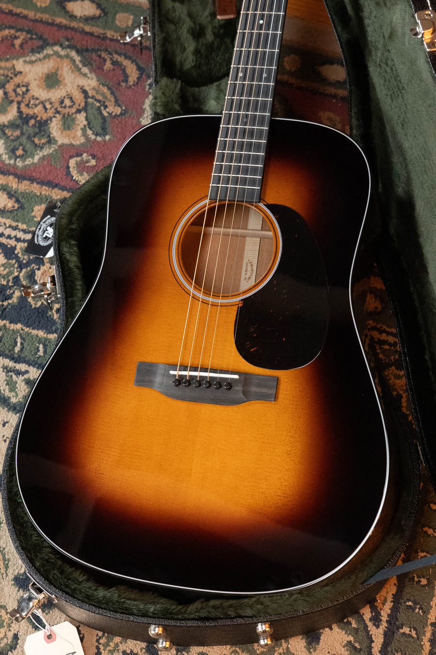 A Martin & Co. D-18 Spruce/Mahogany 1935 Gloss Sunburst Finish Dreadnought Acoustic Guitar #8004 rests in an open green velvet-lined case atop a patterned rug.