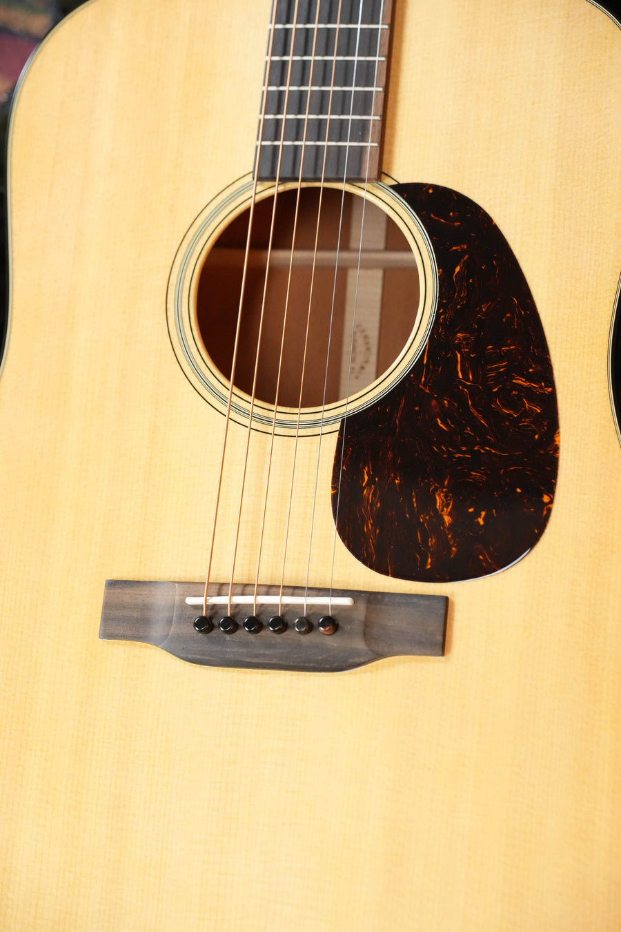 Close-up of a Martin & Co. D-18 Spruce/Mahogany Gloss Finish Dreadnought Acoustic Guitar #5420, showing the sound hole, pickguard, bridge, and strings on its light spruce top.