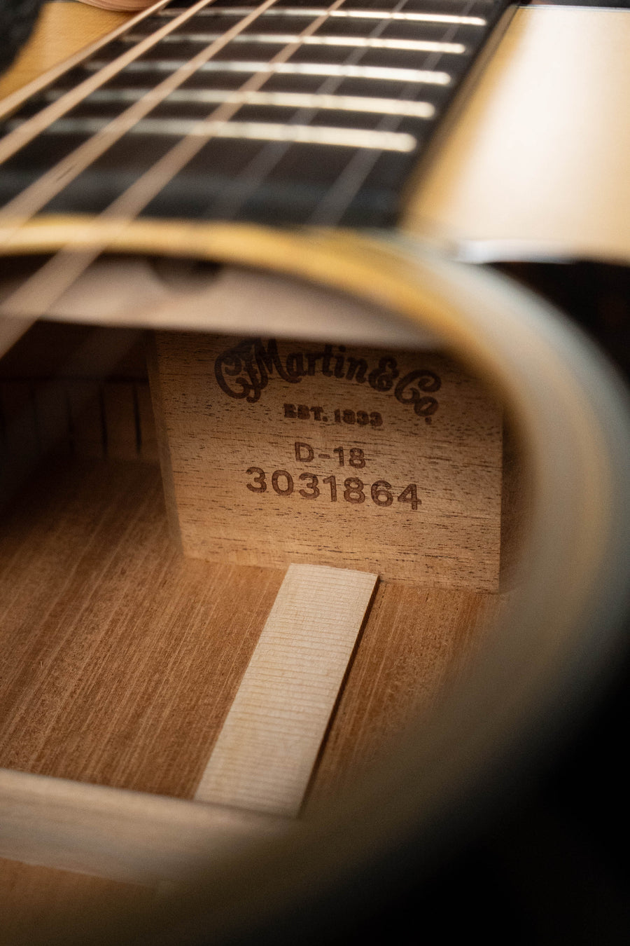 Close-up inside a Martin & Co. D-18 Spruce/Mahogany Satin Finish Dreadnought Acoustic Guitar #1864, showing the label through the sound hole beneath the fretboard, with its mahogany back and sides visible.