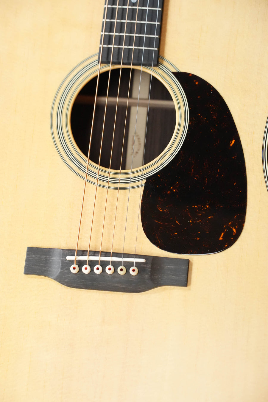 Close-up of the Martin & Co. D-28 Satin Spruce/Rosewood Acoustic Guitar #3679, showing the sound hole, six strings, black pickguard, and bridge on a light wood satin-finish body.